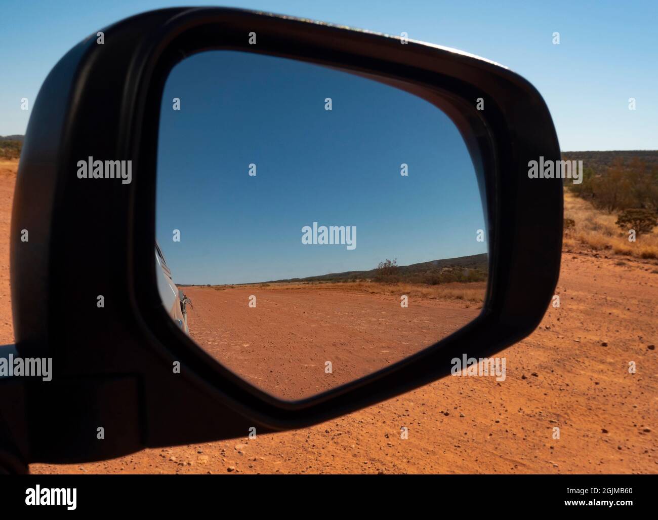 Outback central Australia red centre remote unsealed dirt gravel road track viewed from rear view mirror. Stock Photo