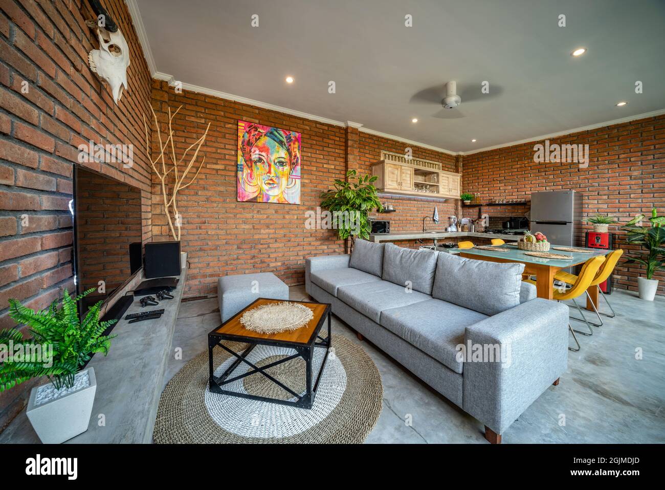 Canggu, Bali, Indonesia, 12 August 2018. Beautiful living room interior with orange brick walls and view of kitchen in new luxury home. Home Interior Stock Photo