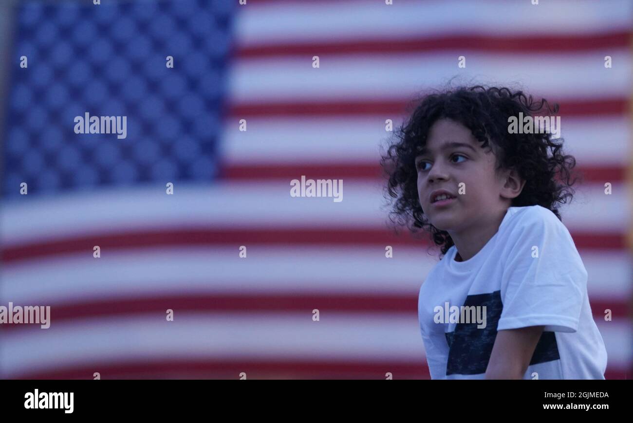 St. Louis, USA. 10th Sep, 2021. Victor Kudrnka (9) listens as the names of those killed at the World Trade Centers, and the servicemen and women who have been killed in war since the 9/11 attacks are read at dusk on Art Hill in St. Louis on Friday, September 10, 2021. The are 7400 American flags on display to honor their memory. Photo by Bill Greenblatt/UPI Credit: UPI/Alamy Live News Stock Photo