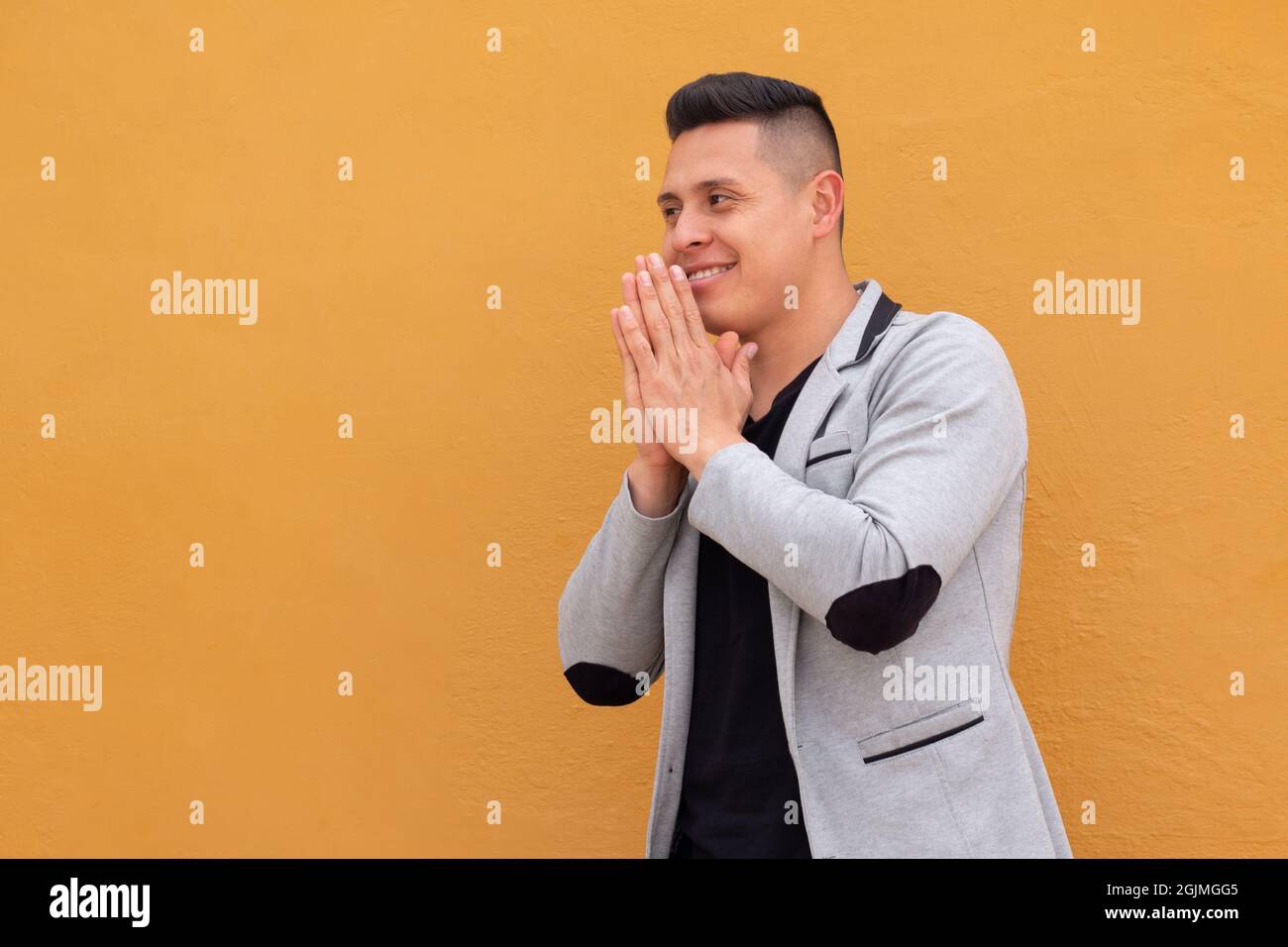 Latin man clasping his hands together and waiting anxiously for something.  Stock Photo