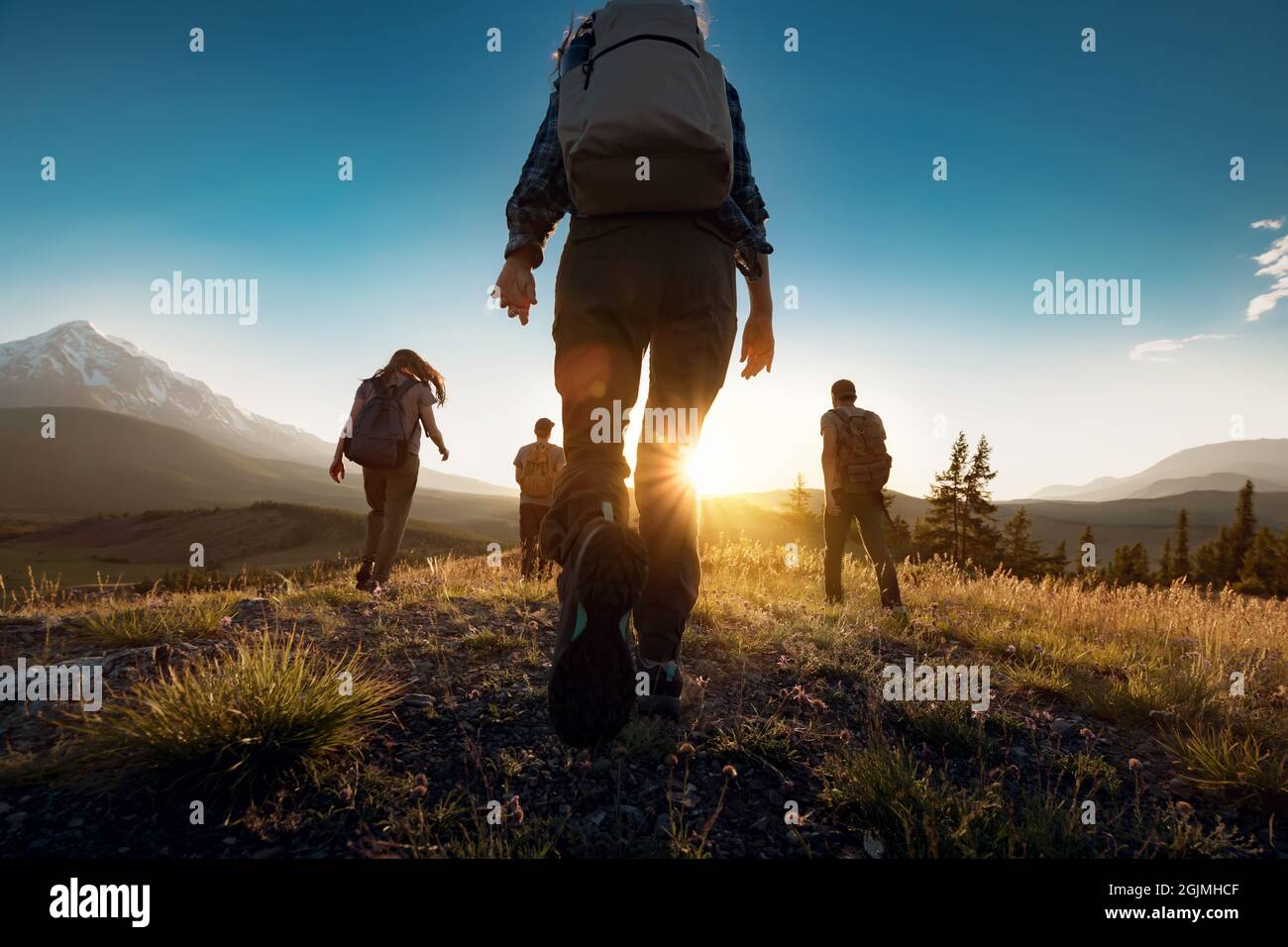 Group of sporty people walks in mountains at sunset with backpacks. Altai mountains, Siberia, Russia. Stock Photo