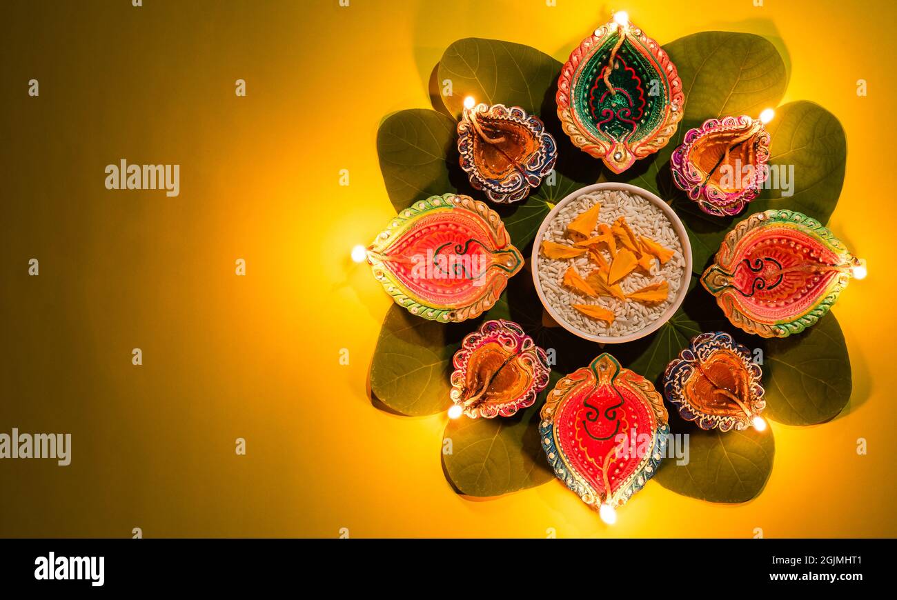Happy Dussehra. Clay Diya lamps lit during Dussehra with yellow flowers, green leaf and rice. Dussehra Indian Festival concept. Stock Photo