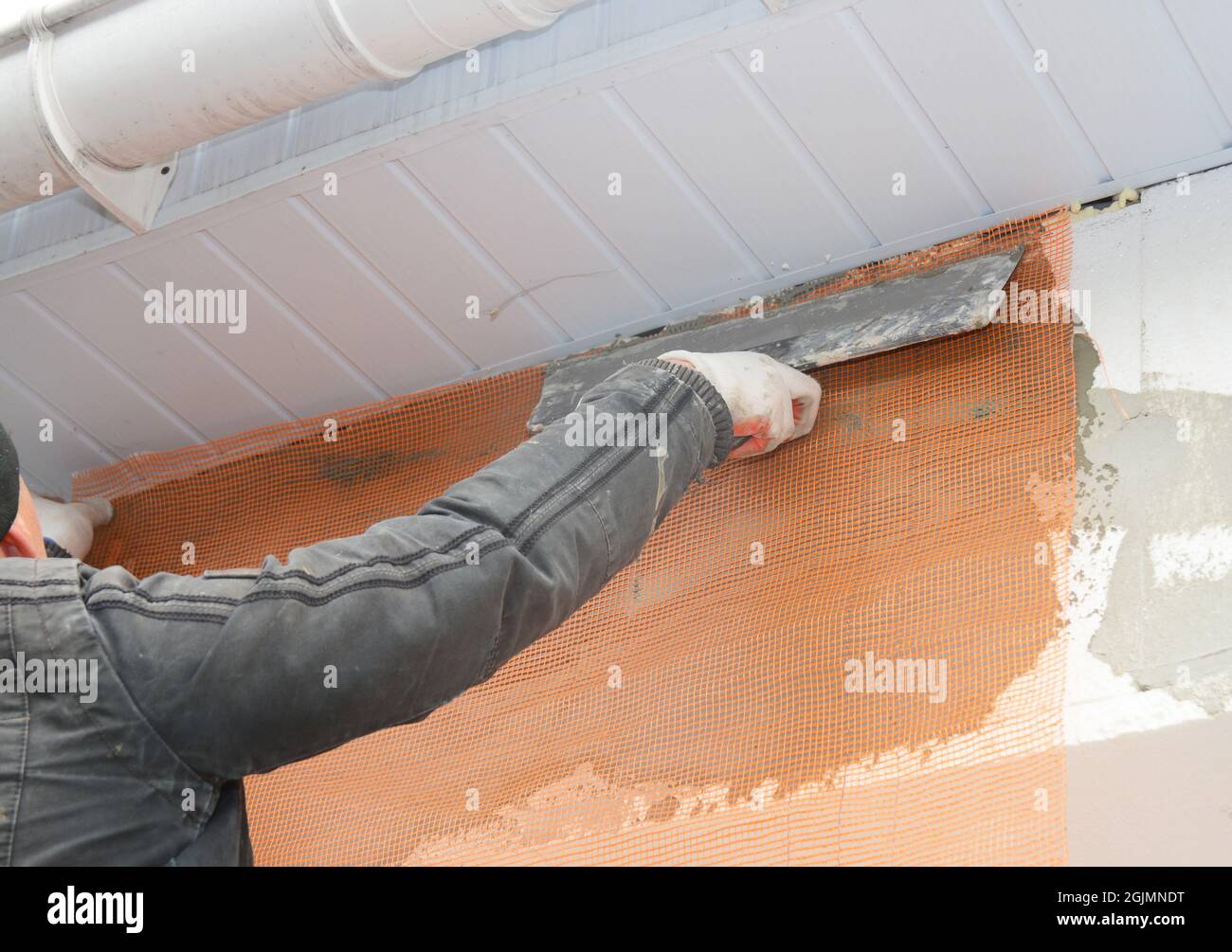 Contractor plastering wall with putty knife, fiberglass mesh, plaster mesh after rigid