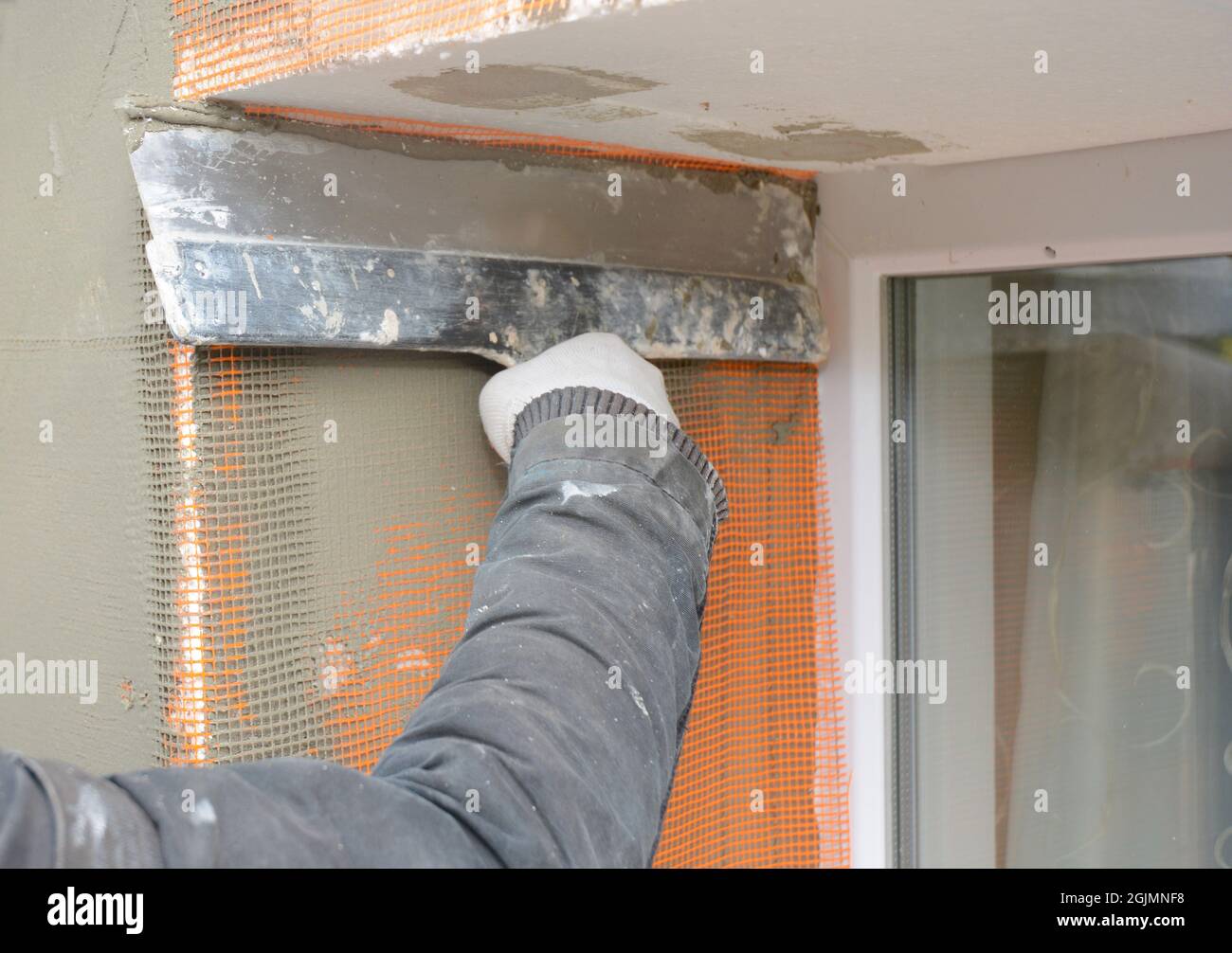 Contractor plastering wall with putty knife, fiberglass mesh, plaster mesh after rigid