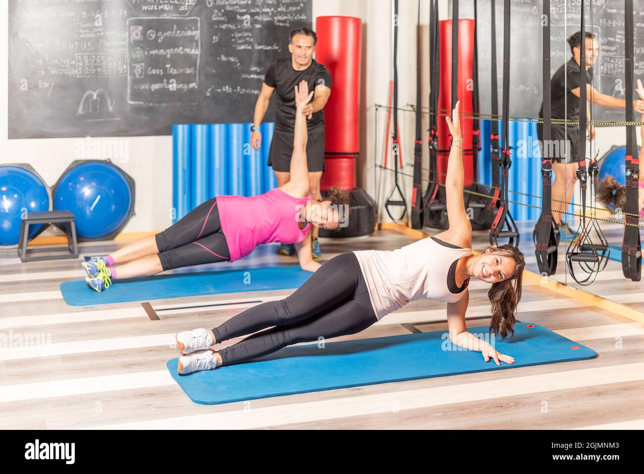 People doing lateral plank exercise in gym Stock Photo