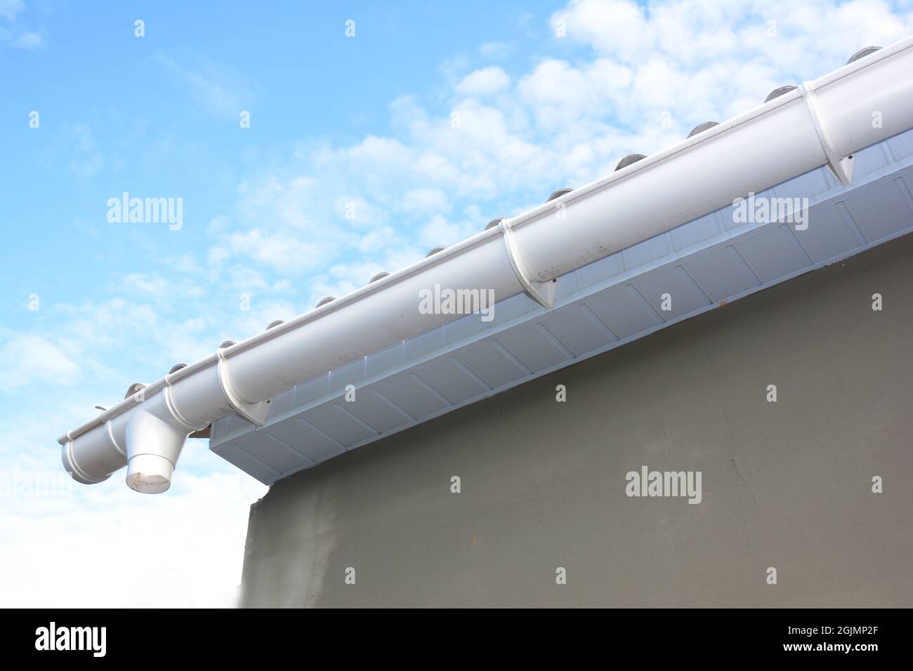 Roof gutter repair. Rain gutter installation with holders, drain downspout pipe. Unfinished