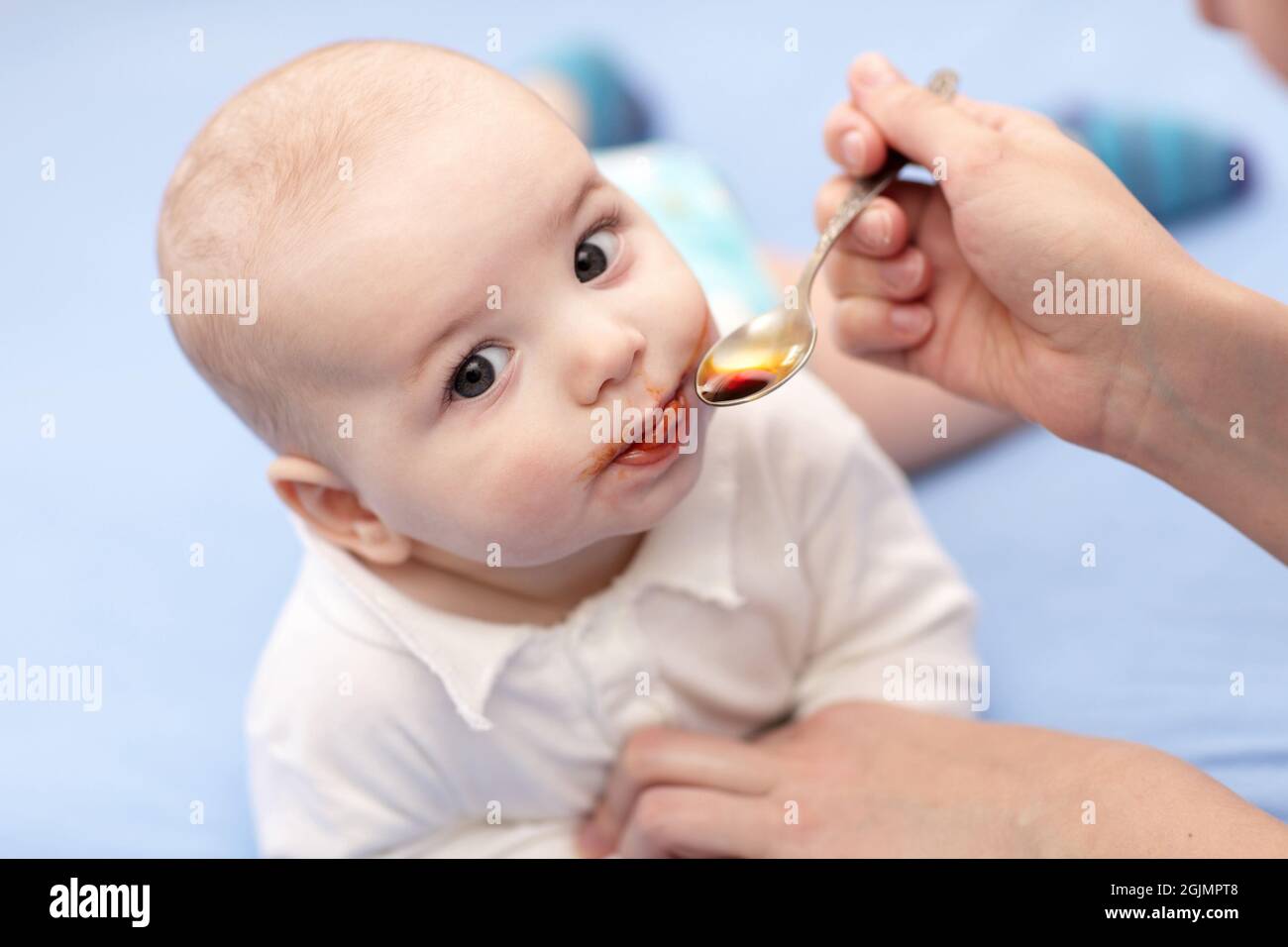 A mother giving a spoon of iron syrup to her baby Stock Photo