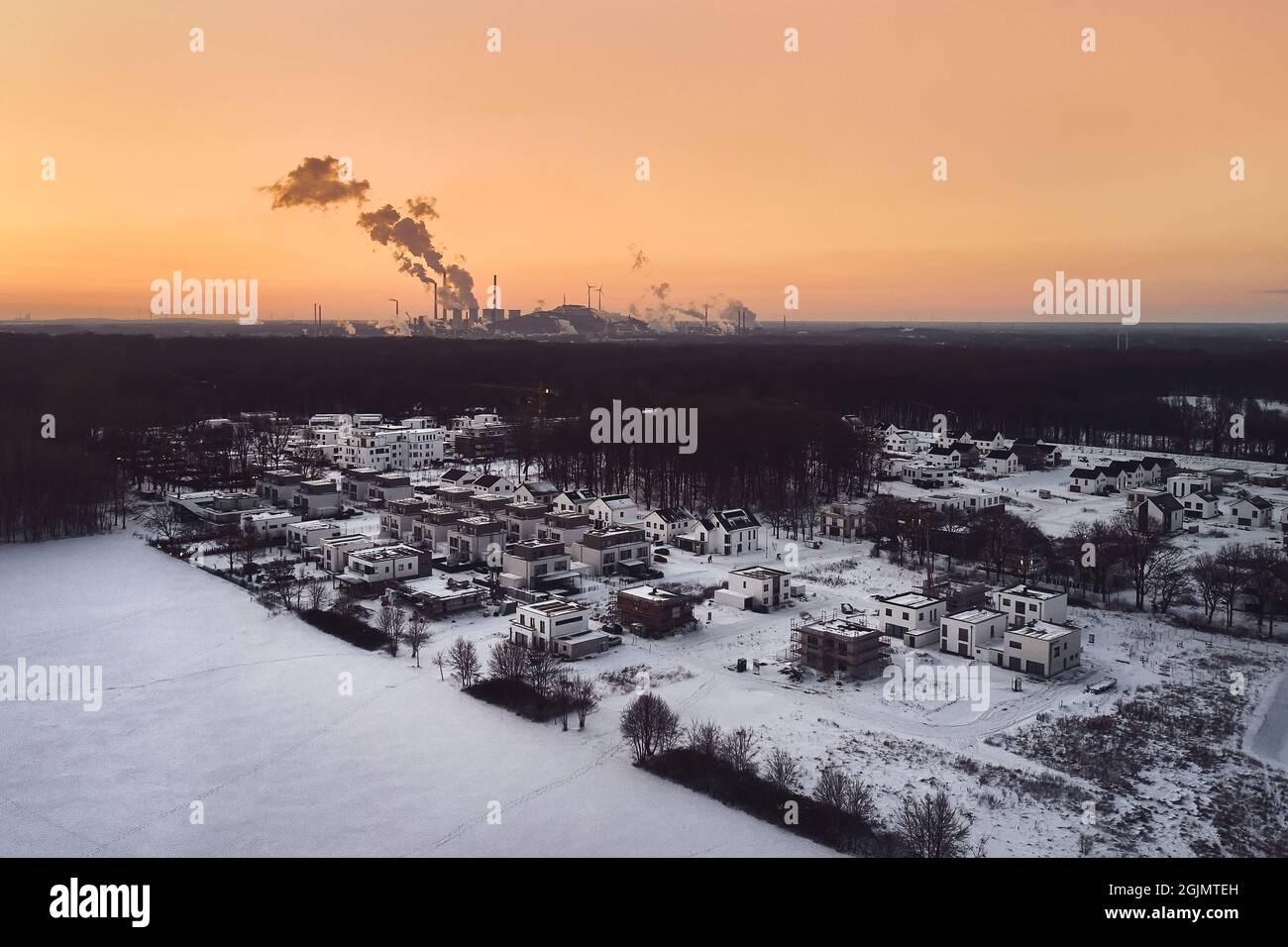 Drone image from a residential area covered with snow and industrial factory during sunset in Germany Stock Photo