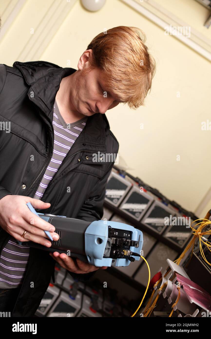 The technician looking at a reflectometer in a telecom site Stock Photo