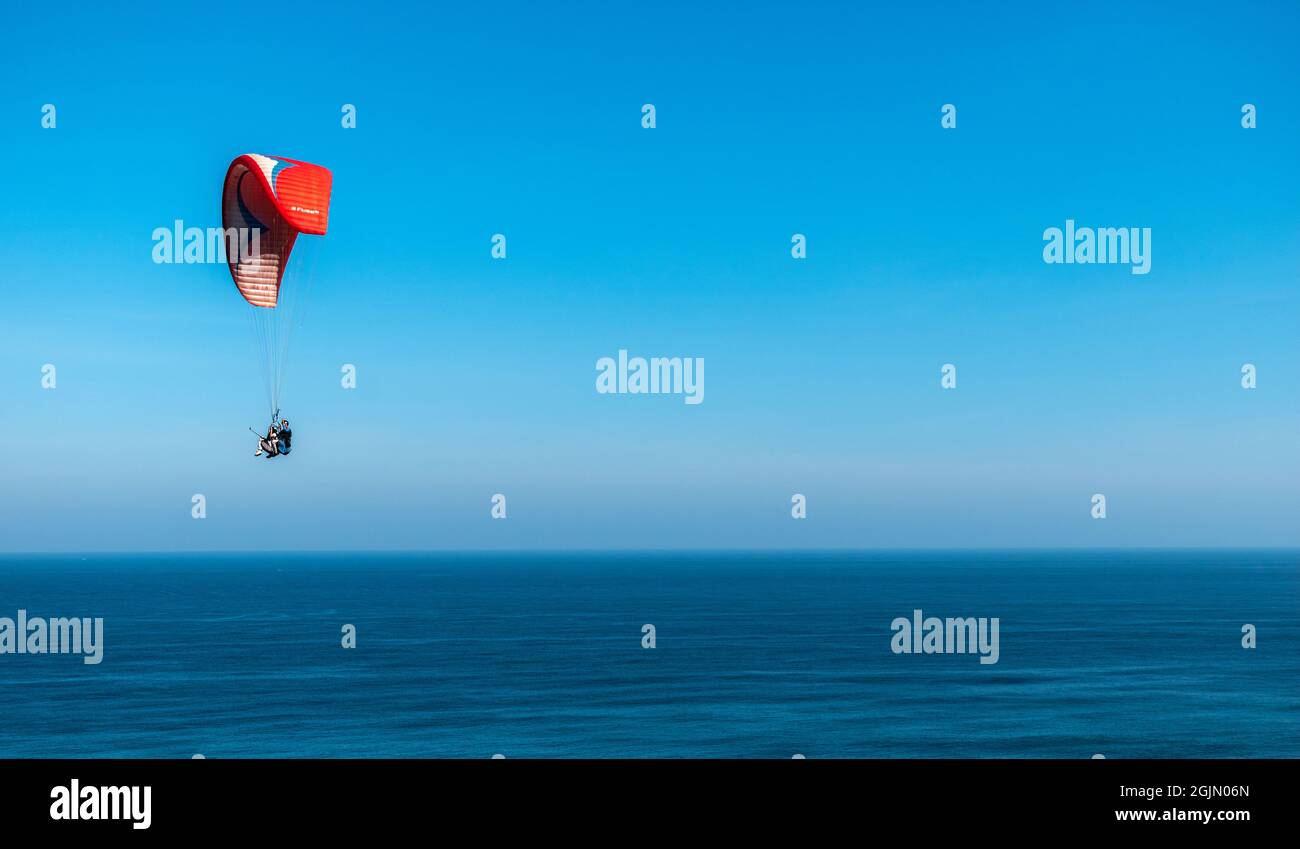 paragliders flies over the ocean Stock Photo