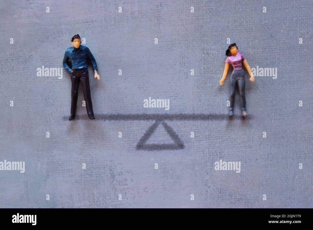 Gender equality concept. Miniature man and woman standing on balance scale. Stock Photo