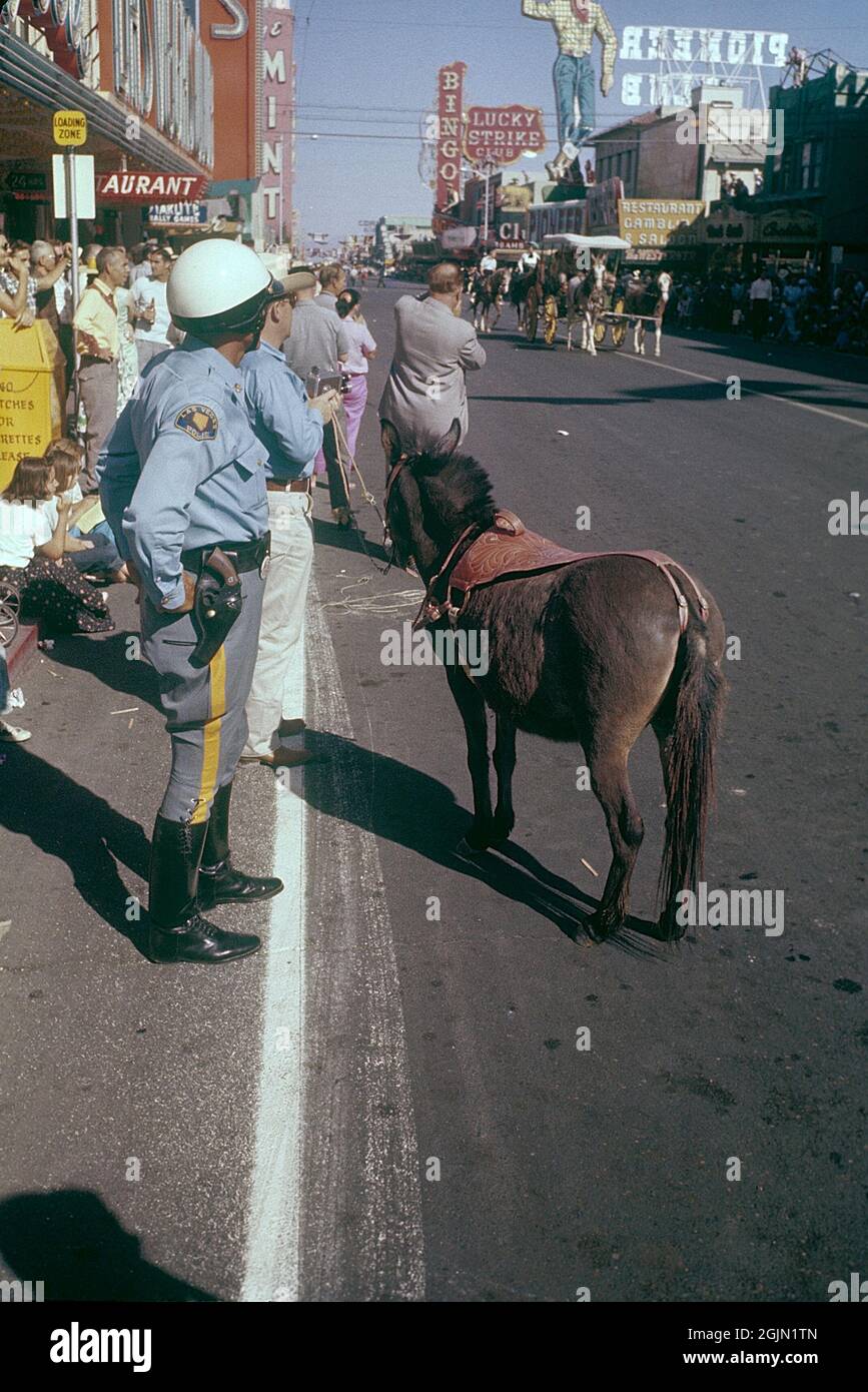 Las Vegas 1959. A parade is passing through downtown Las Vegas and Fremont street and people are standing on the sidewalks looking. In the foreground a policeman in uniform. In the background the classic sign of Pioneer club. Kodachrome slide original.   Credit Roland Palm ref 6-2-9 Stock Photo