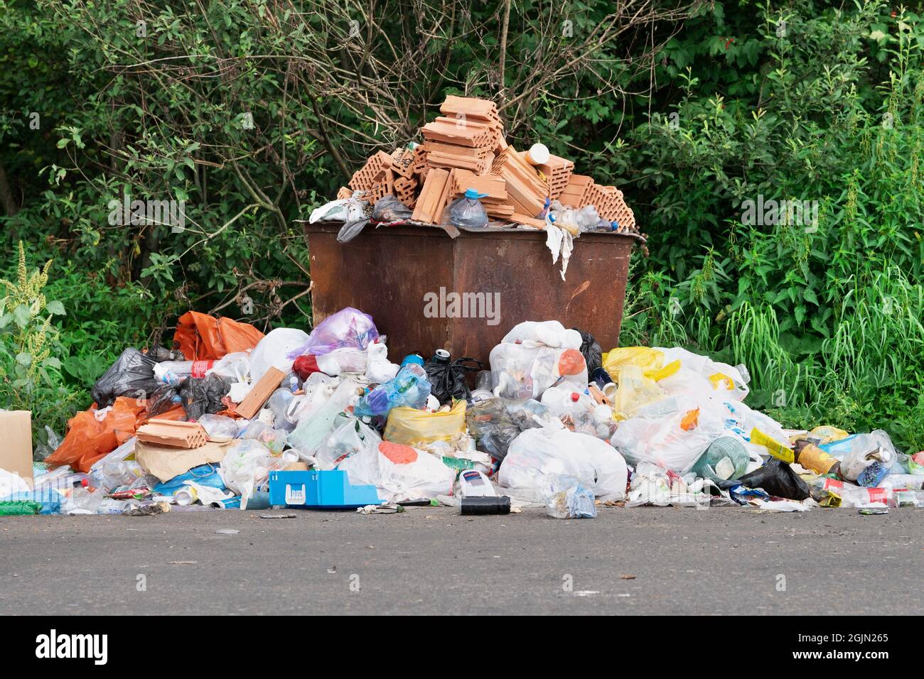 Rusty trash can overflowed with rubbish on the roadside Stock Photo - Alamy