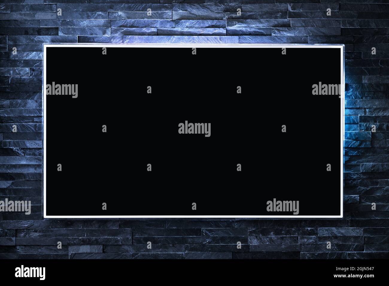 Tv screen on wall at night in dark with led light. Television and flat smart monitor display on blue brick background. Modern futuristic loft. Stock Photo