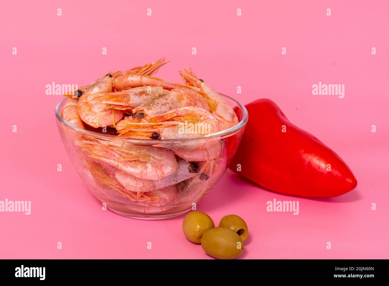 boiled shrimp in a glass bowl and fresh vegetables on a pink background Stock Photo