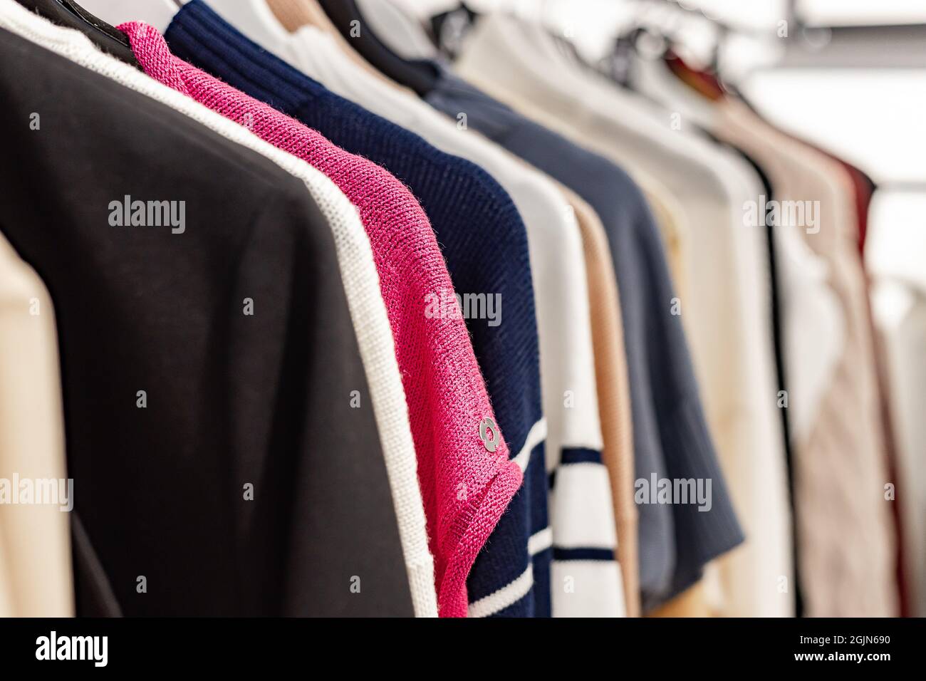 Fashionable stylish women's clothing on a hanger. Knitted dresses and jumpers. Close-up of branded clothing in a show room. Fashion retail, show room, Stock Photo