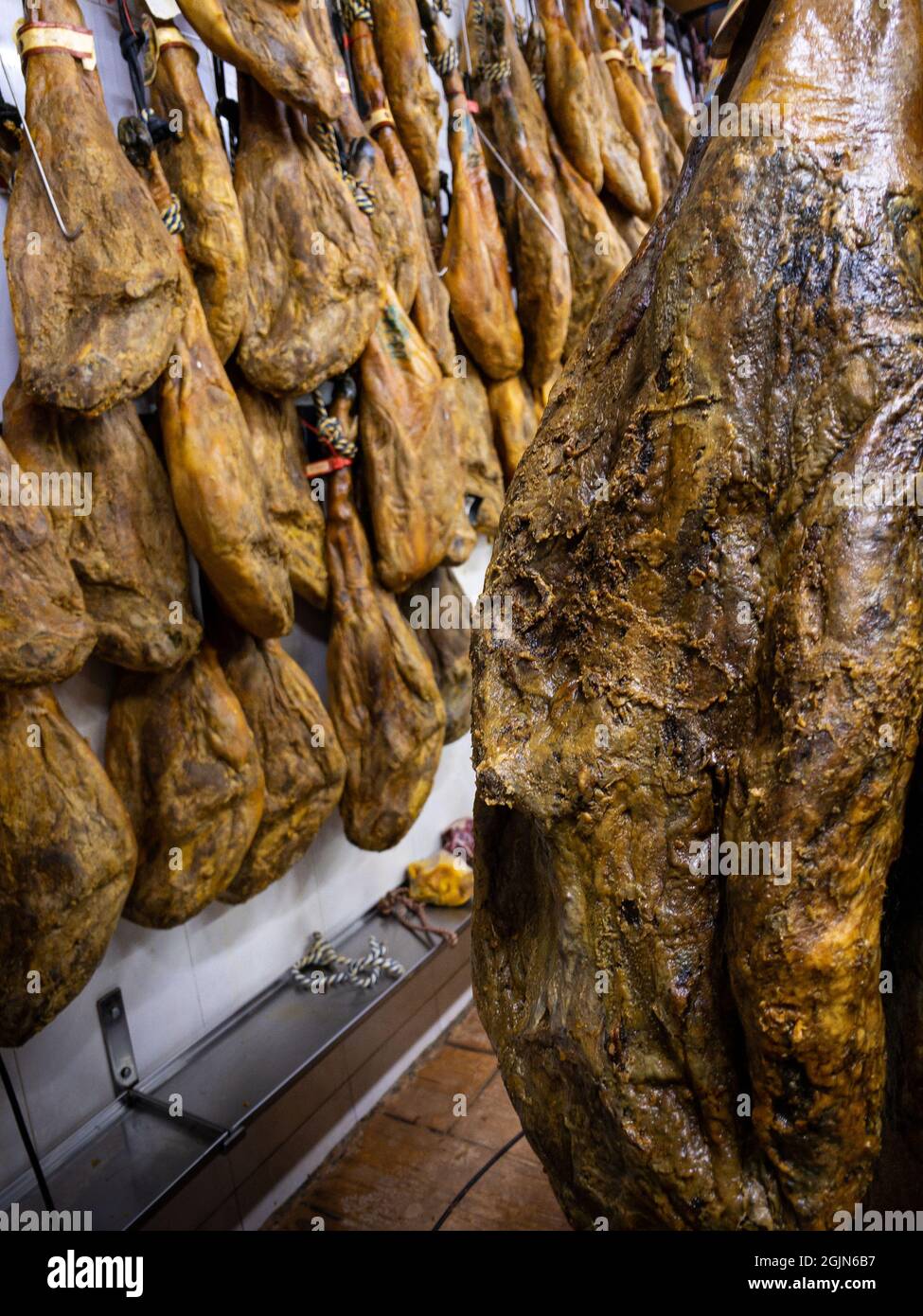 Dried pork thighs hang on the meat market. Spanish national dish of ham or jamon in a grocery. Iberian pork shopping in supermarket Spain. Dry and cur Stock Photo