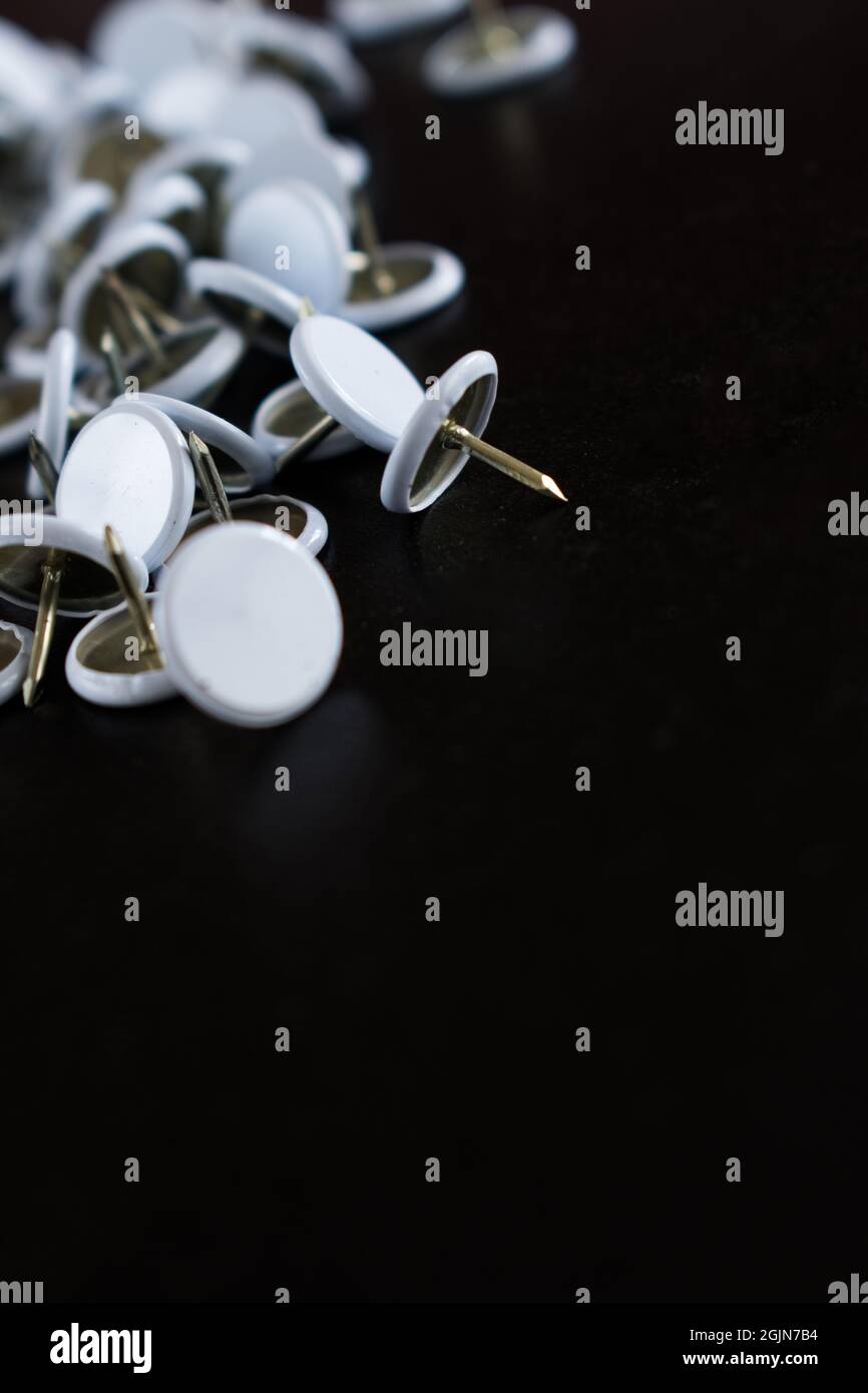 Vertical shot of white drawing pins on a black surface Stock Photo