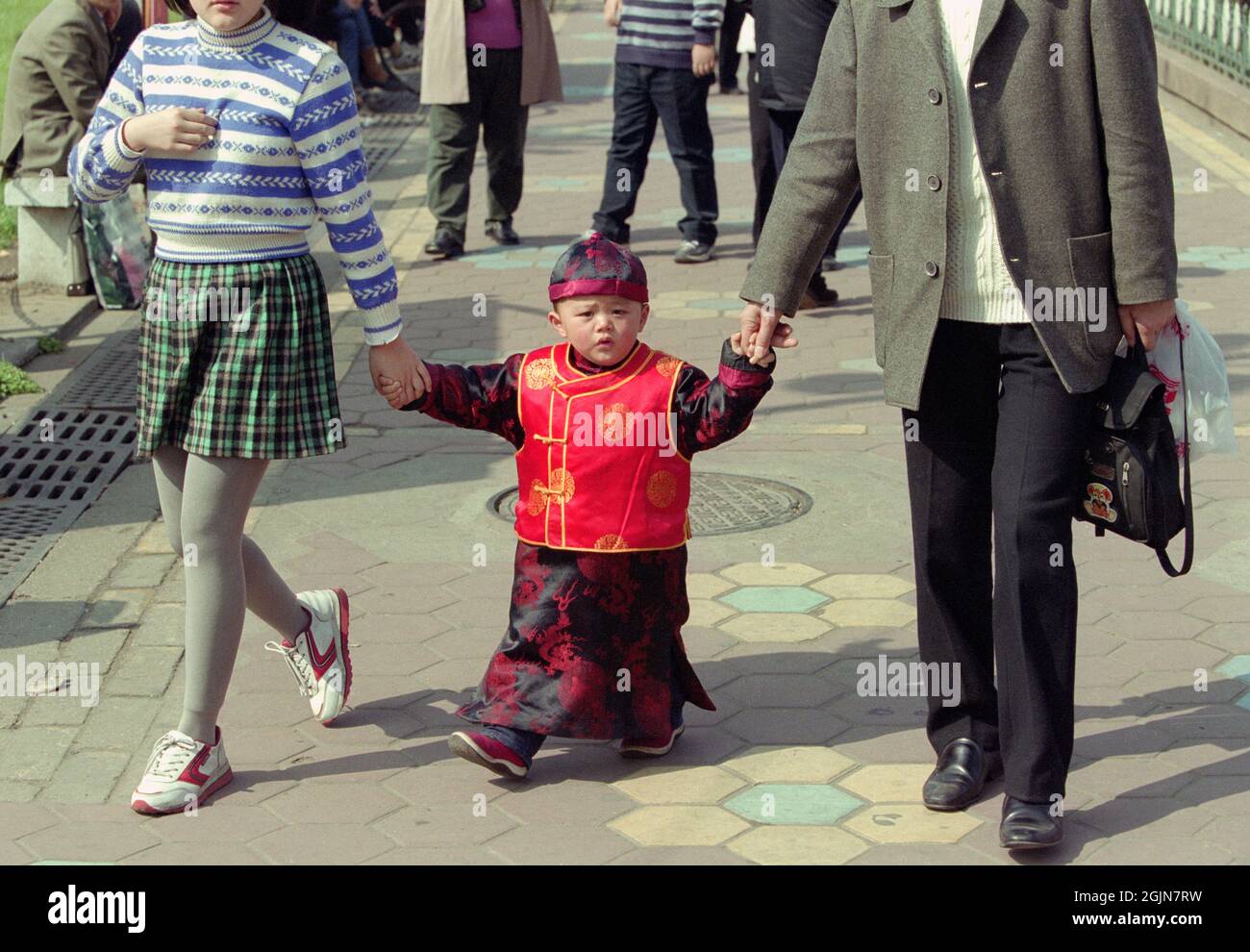 A Chinese boy dressed as a little emperor holds the hands of his parents in Nanchang, Jiangxi, China. Photo taken around 2000. Stock Photo