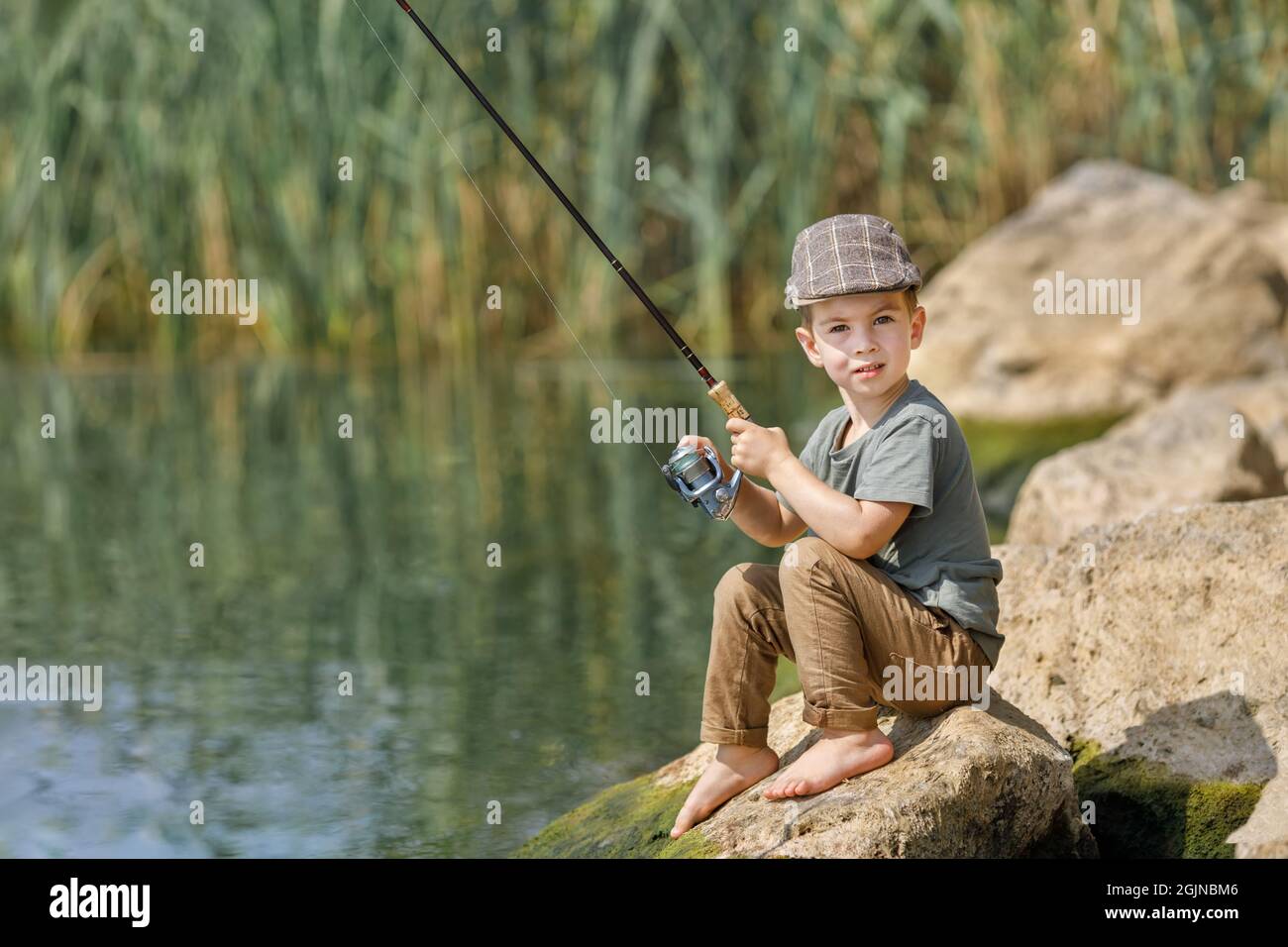 https://c8.alamy.com/comp/2GJNBM6/little-boy-sitting-on-stone-and-fishing-2GJNBM6.jpg