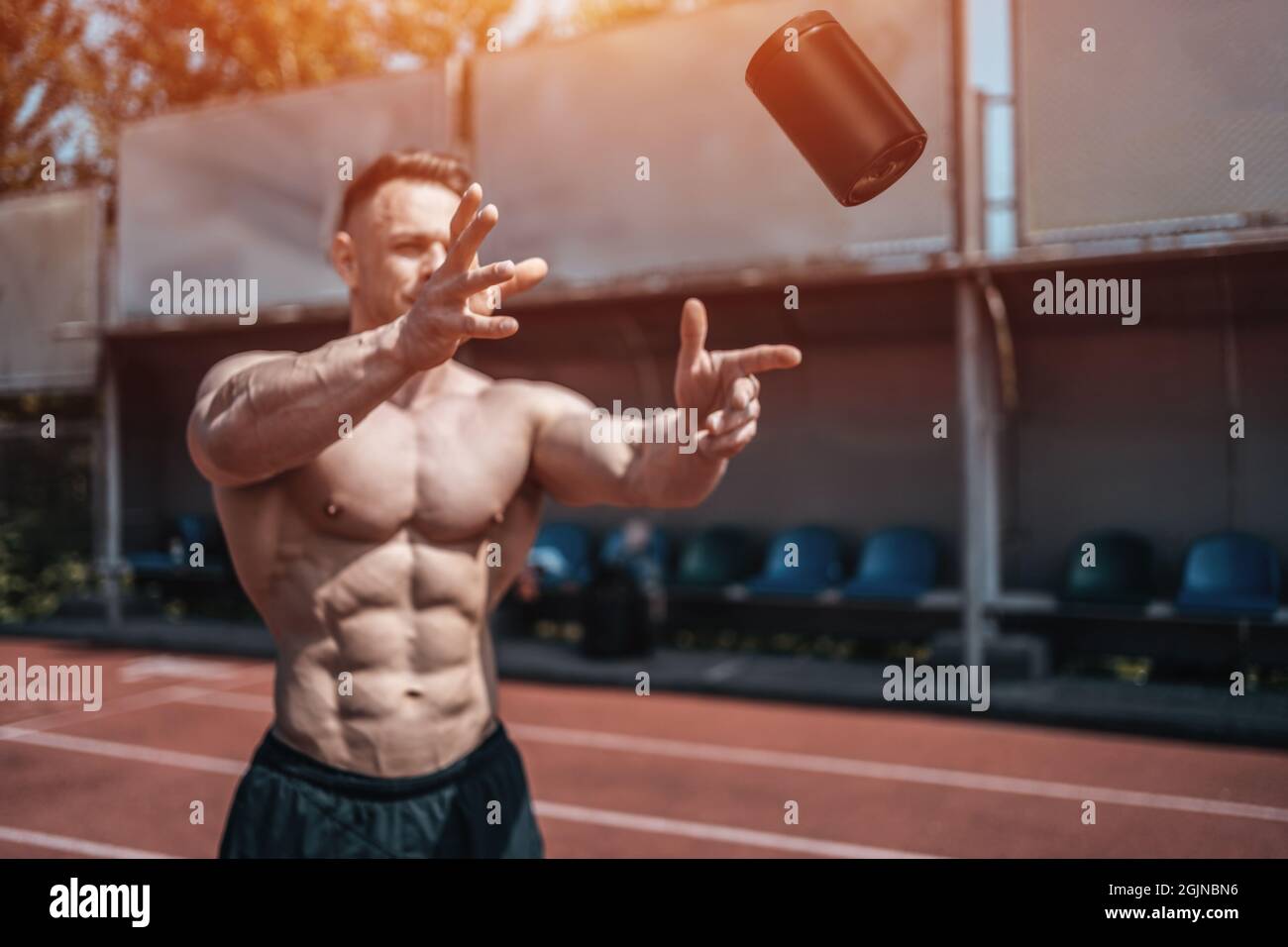 muscular athlete man throw up black container with protein whey powder outdoor Stock Photo