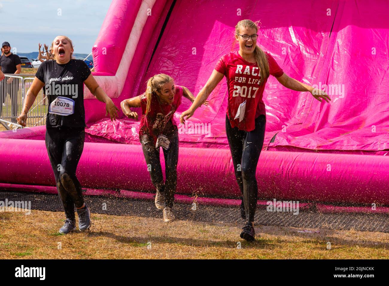 Baiter Park, Poole, Dorset, UK. 11th September 2021. Race for Life Poole Pretty Muddy returns after being cancelled last year due to Covid-19, with hundreds many dressed in pink, joining the fight to beat cancer and raise money for Cancer Research UK, negotiating obstacles throughout the 5km course and have fun getting covered in mud. Having fun on the inflatable slide. Credit: Carolyn Jenkins/Alamy Live News Stock Photo