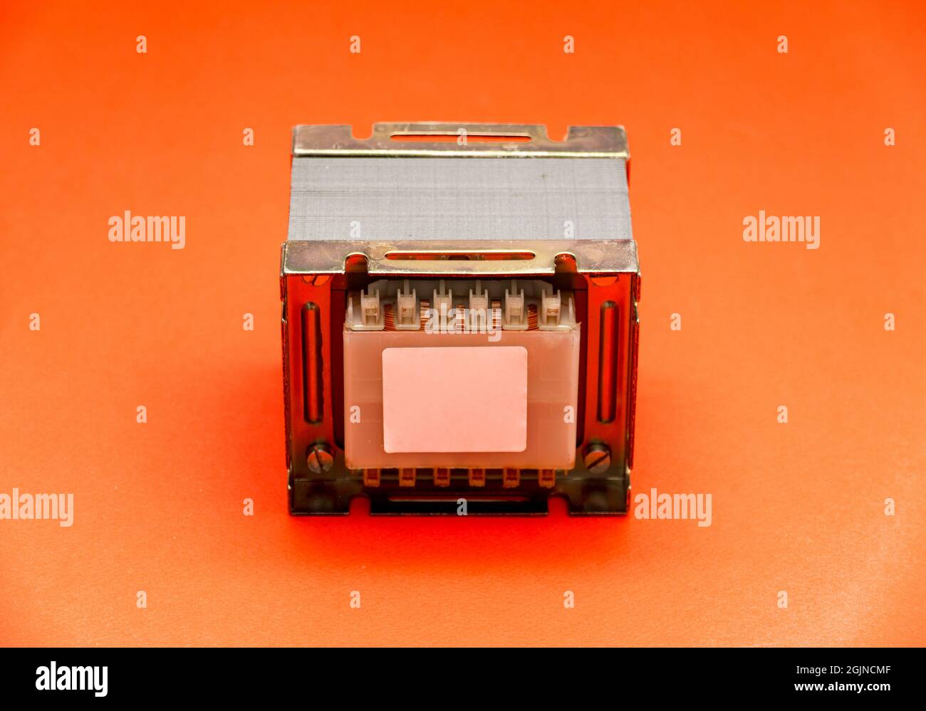 Electrical transformer (square type) for mains voltage reduction isolated on red background Stock Photo
