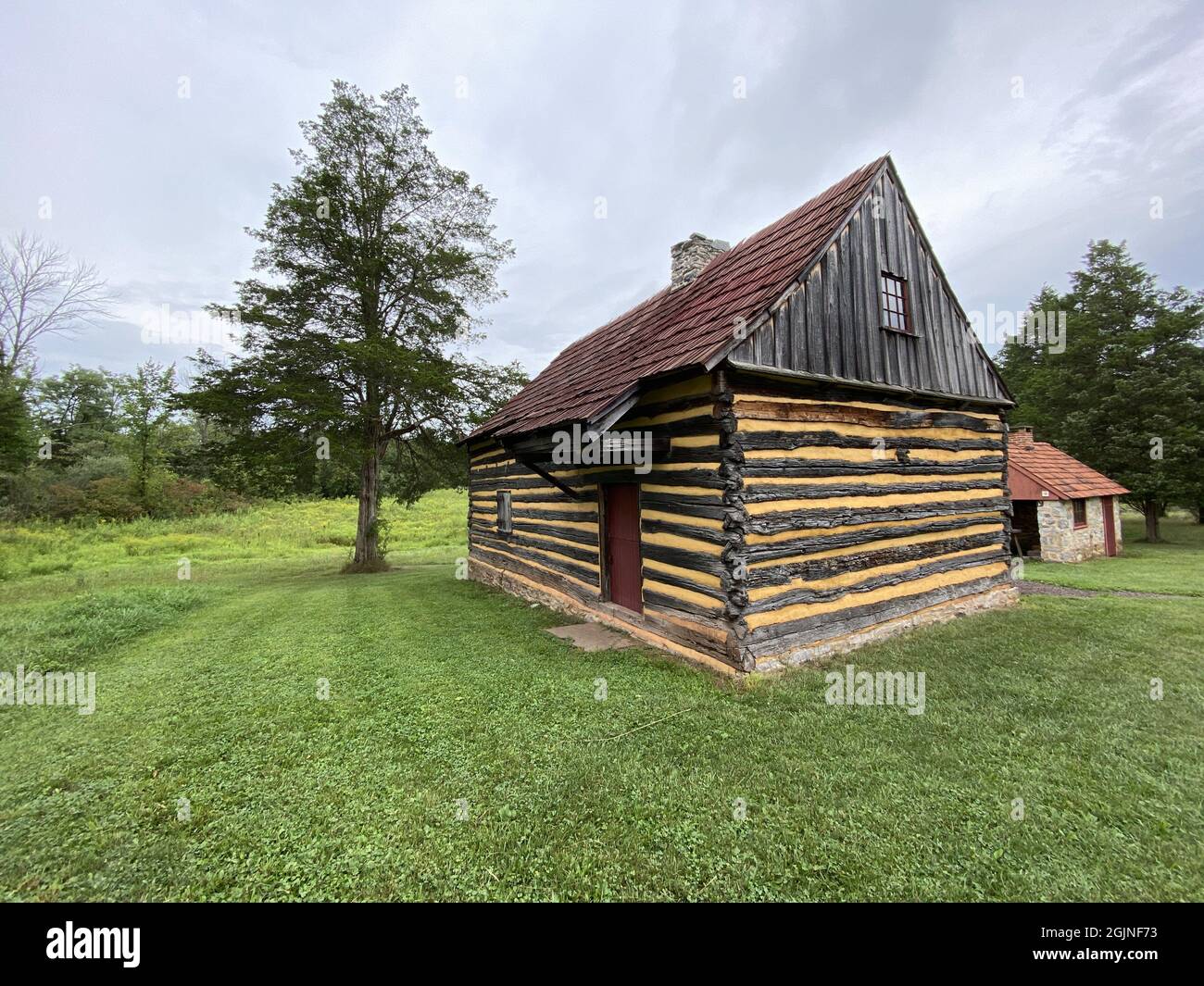 Traditional old wooden house on the grassy field in the woods in the