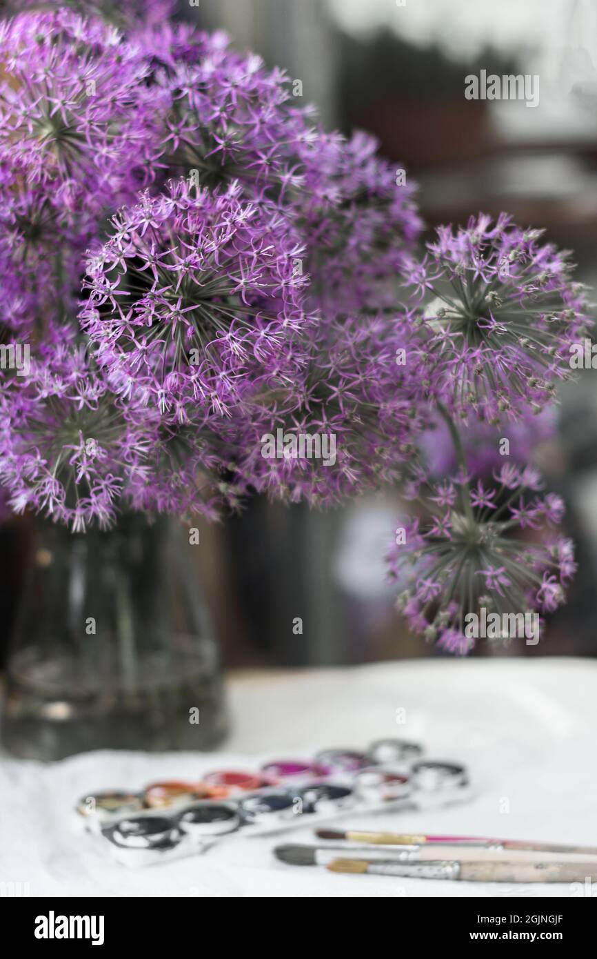 bouquet of blooming decorative onions of violet-lilac color close-up  selective focus in a glass vase stands on the table next to brushes and  watercolo Stock Photo - Alamy