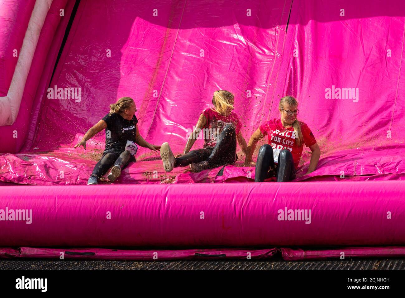 Baiter Park, Poole, Dorset, UK. 11th September 2021. Race for Life Poole Pretty Muddy returns after being cancelled last year due to Covid-19, with hundreds many dressed in pink, joining the fight to beat cancer and raise money for Cancer Research UK, negotiating obstacles throughout the 5km course and have fun getting covered in mud. Having fun on the inflatable slide. Credit: Carolyn Jenkins/Alamy Live News Stock Photo