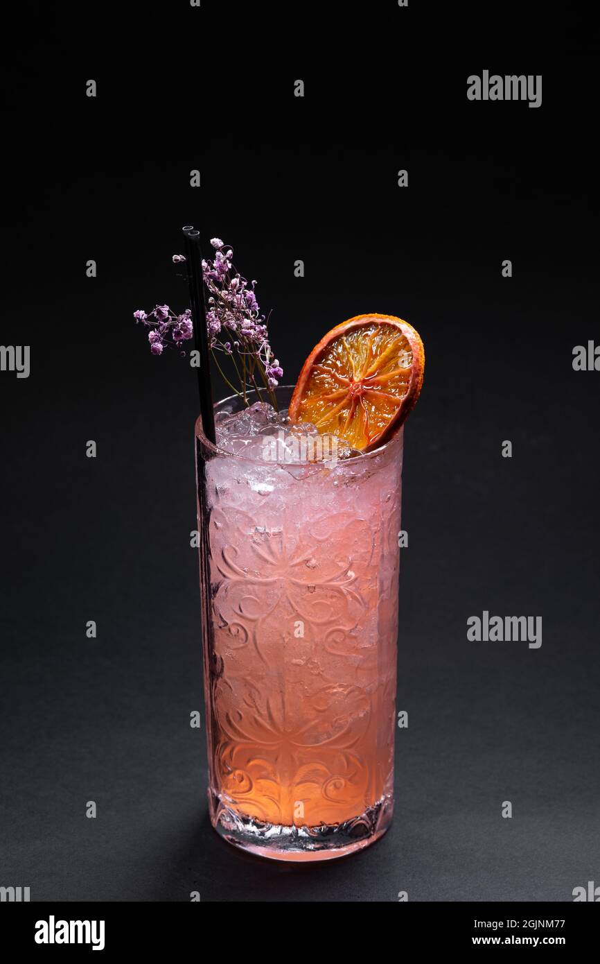 luxury lemonade drink or pink cocktail with ice in glass on black