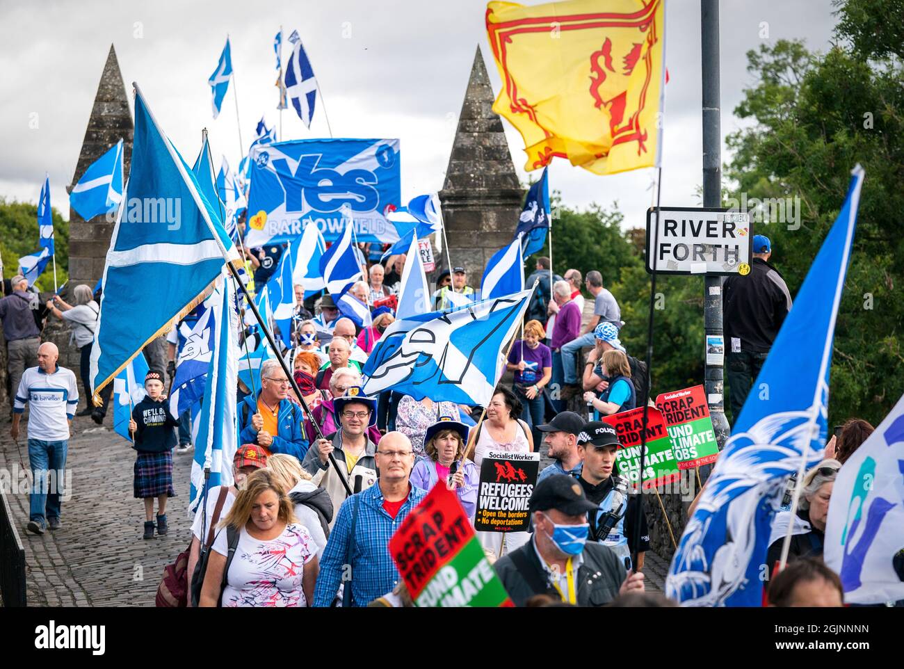 Supporters of Scottish independence march over the Auld Brig on their way to the site of the Battle of Bannockburn for an 'All Under One Banner' rally in Bannockburn, Stirling. The site of the Battle of Bannockburn, is where the army of the King of Scots Robert the Bruce defeated the army of England's King Edward II in 1314, during the first war of Scottish Independence. Picture date: Saturday September 11, 2021. Stock Photo