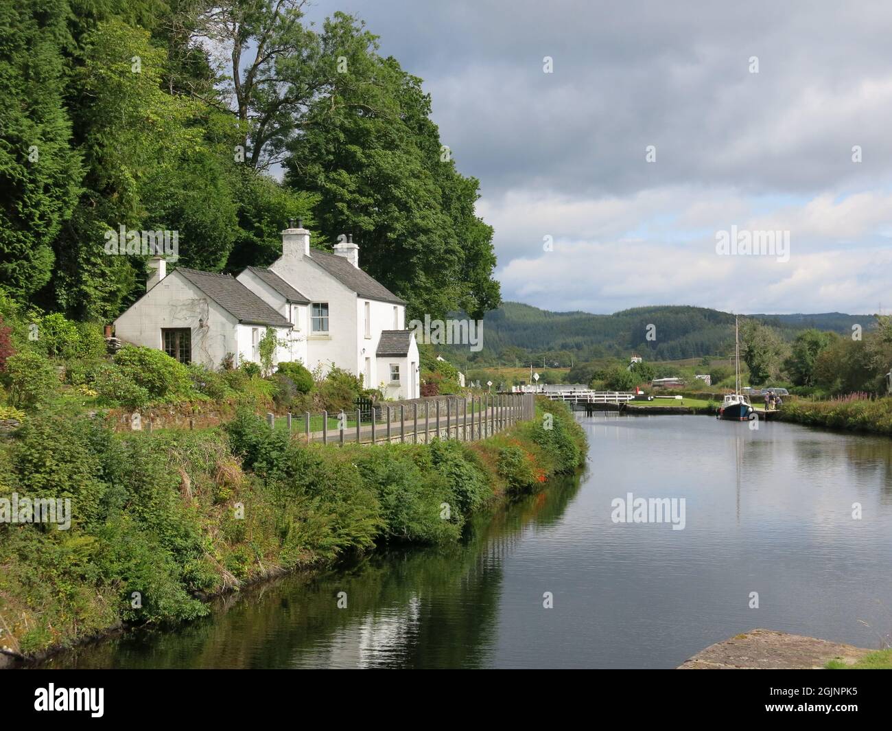 Picturesque scene on Scottish canals: traditional white cottage on the side of the Crinan Canal in Argyll & Bute, cutting across the Kintyre peninsula Stock Photo