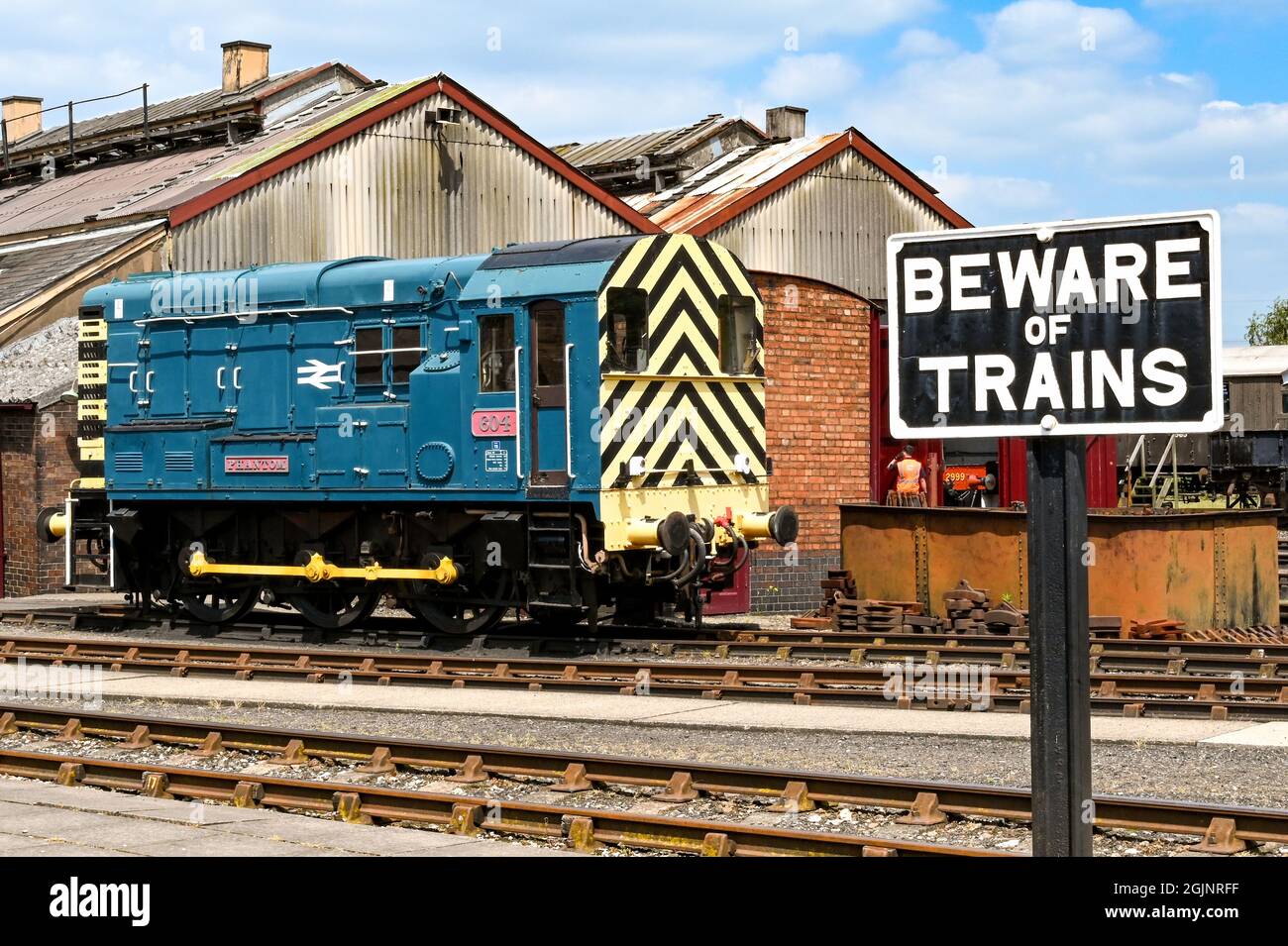 Didcot, Oxfordshire, England - June 2021: Beware of Trains sign alongside railway tracks at the Didcot Railway Centre. In the background is a diesel Stock Photo