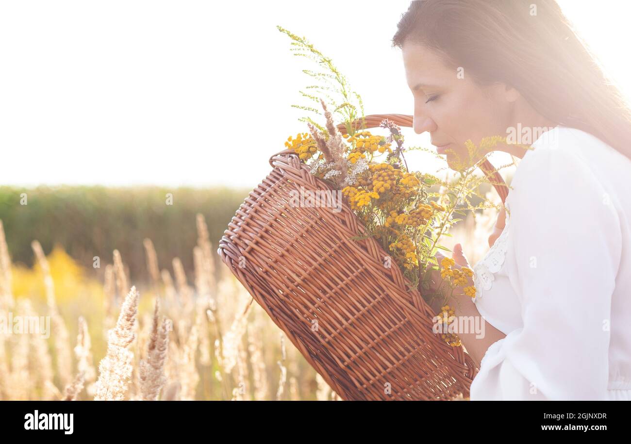 Attractive woman sniffs bouquet of flower herb on open air. Copy space for text. Stock Photo