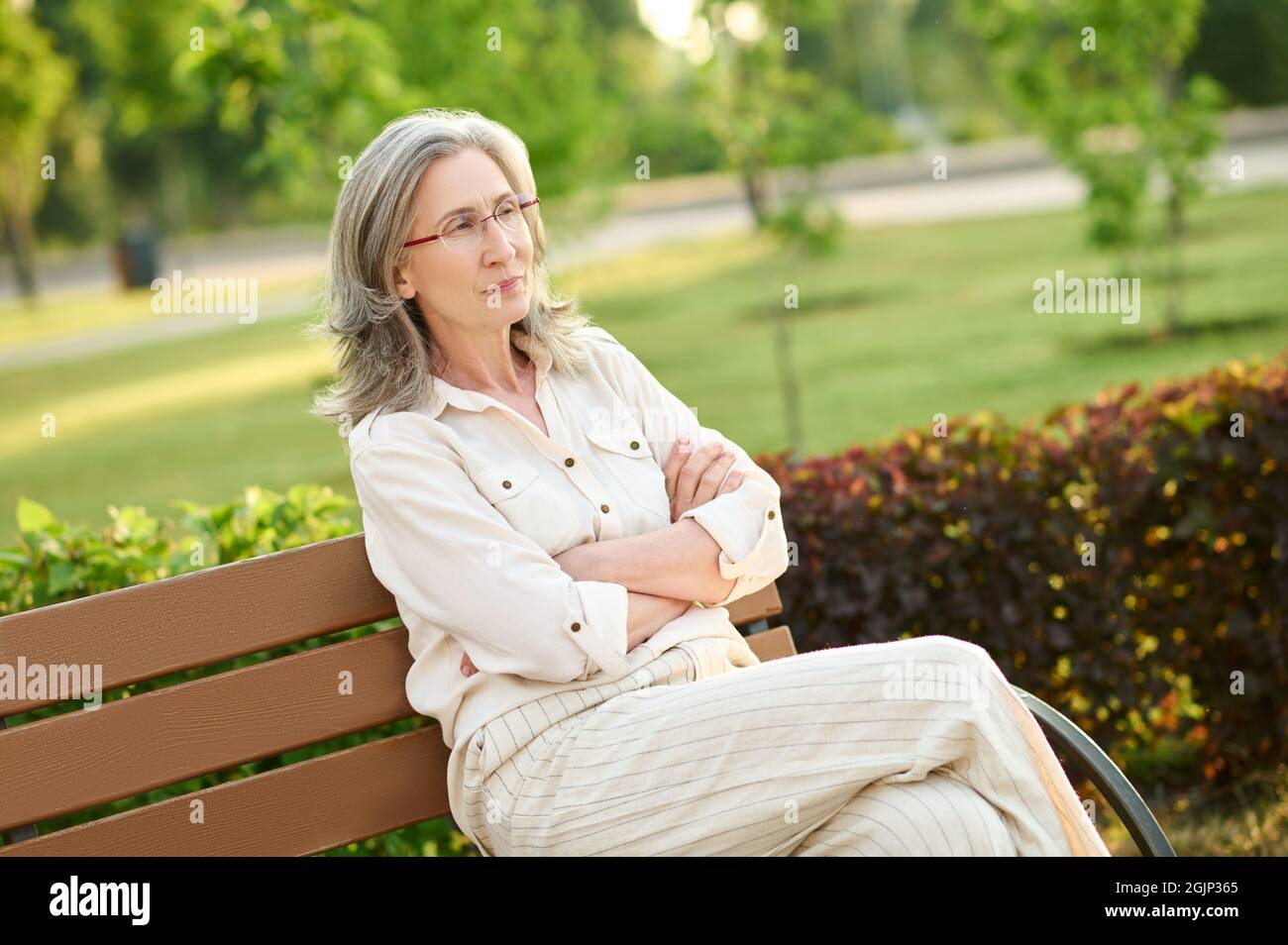 Confident adult woman sitting on park bench Stock Photo