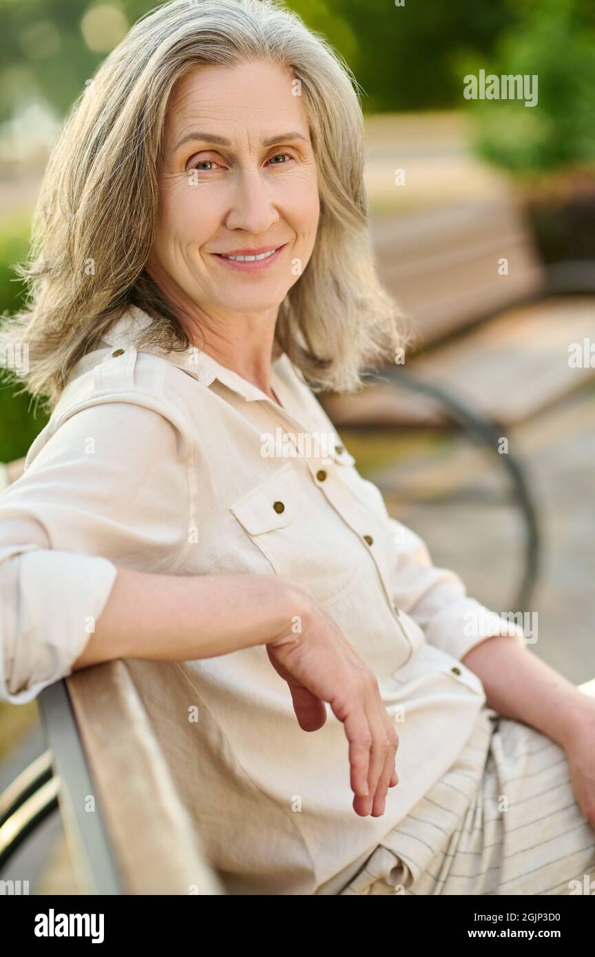 Confident adult woman smiling on bench Stock Photo