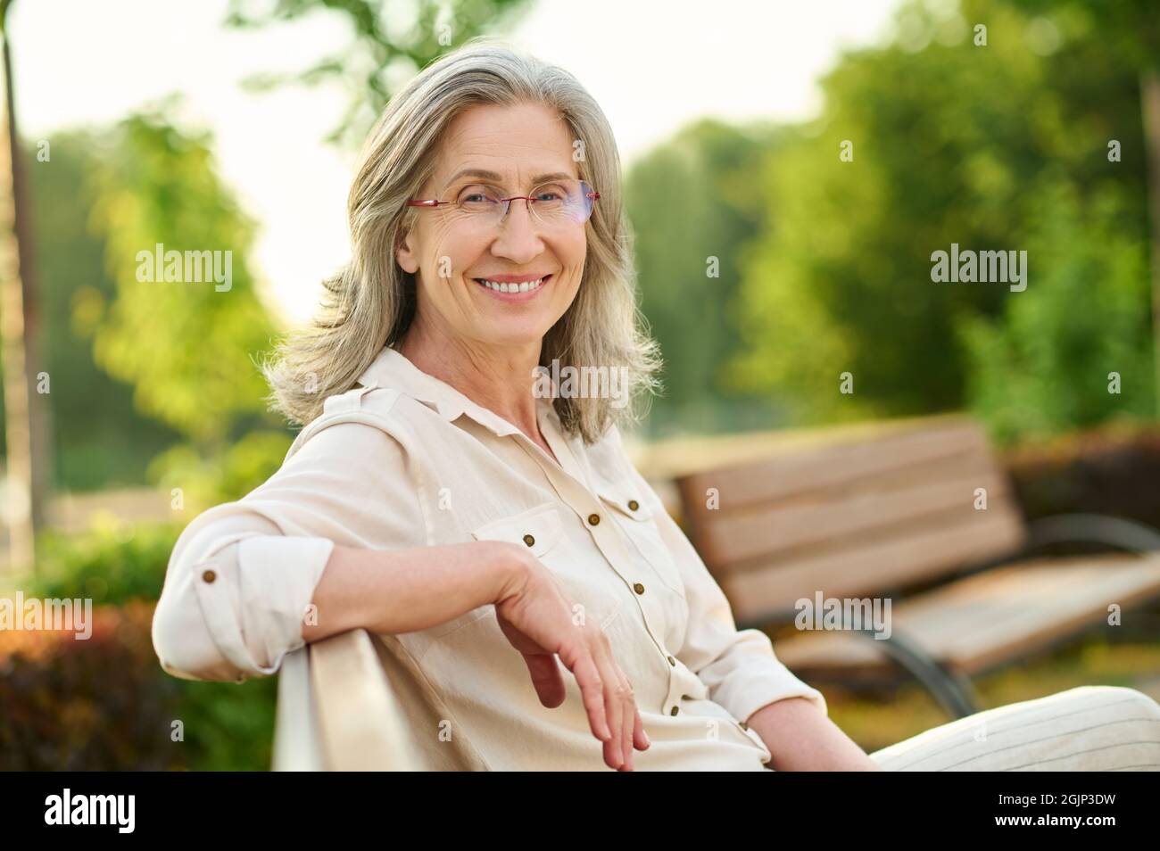 Cheerful woman in glasses having rest outdoors Stock Photo