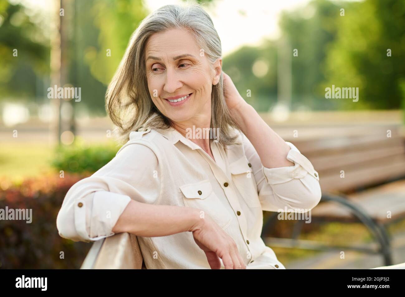 Cheerful cute adult woman sitting on bench Stock Photo