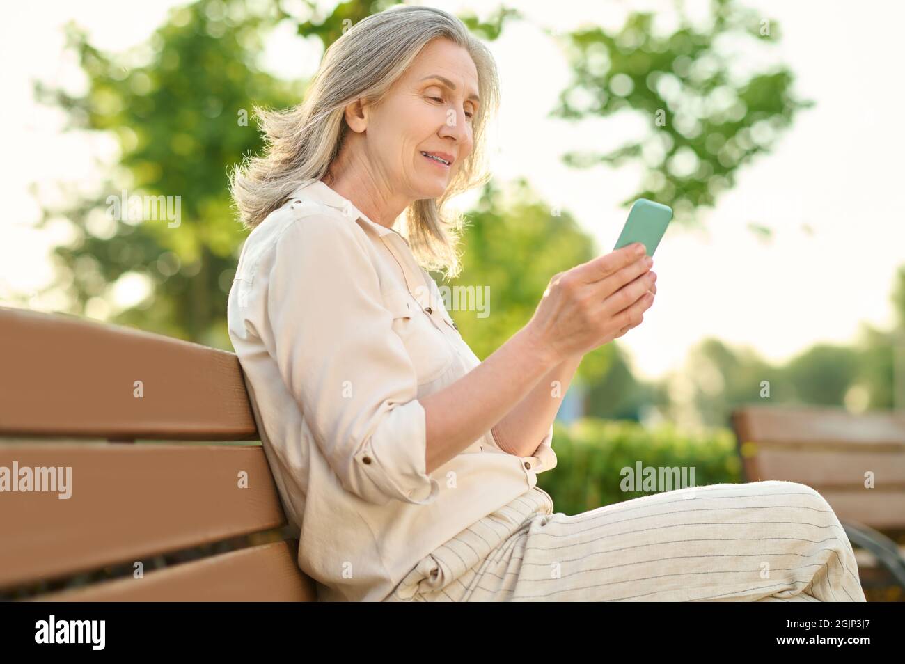 Serious woman with smartphone on bench Stock Photo