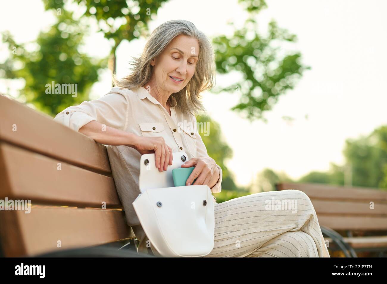 Elegant woman putting smartphone in her handbag Stock Photo