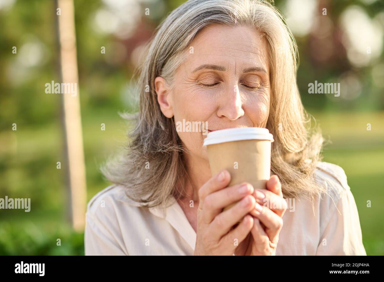 Woman with closed eyes holding glass of coffee Stock Photo