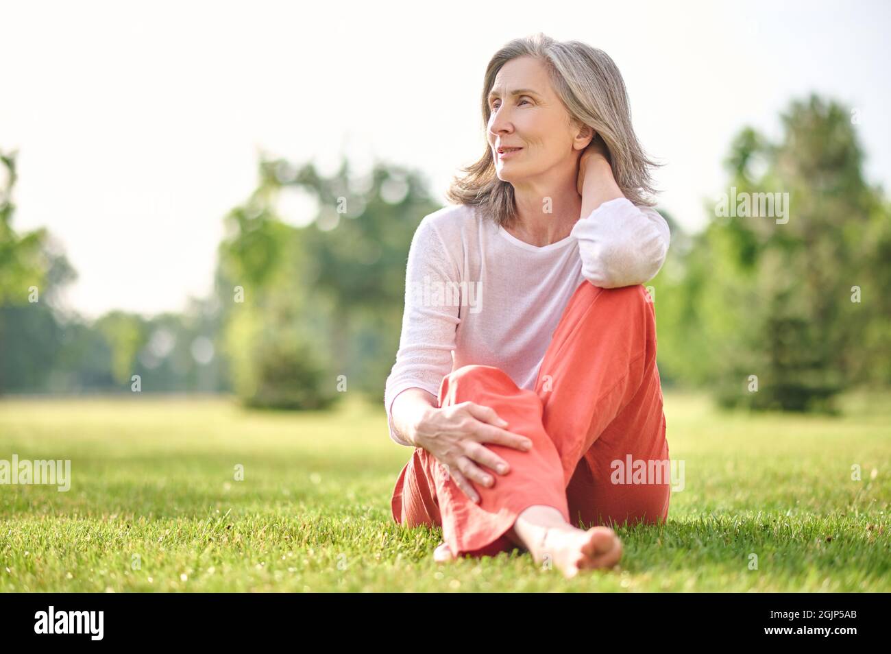 Adult pretty woman meditating on lawn in park Stock Photo