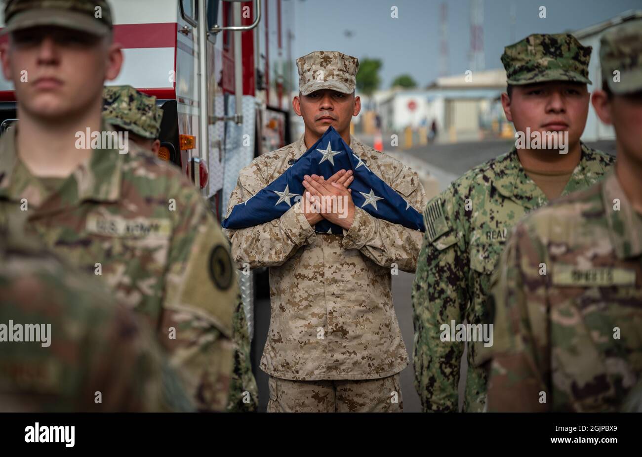 Ambouli, Djibouti. 11th Sep, 2021. U.S. Marine Staff Sgt. Roberto Bravo, center, holds an American flag during a remembrance event on the 20th anniversary of the 9/11 terrorist attacks at Camp Lemonnier September 11, 2021 in Ambouli, Djibouti. The event commemorates the nearly 3,000 people killed by terrorists on September 11th, 2001. Credit: SrA Dwane R. Young/U.S. Air Force/Alamy Live News Stock Photo