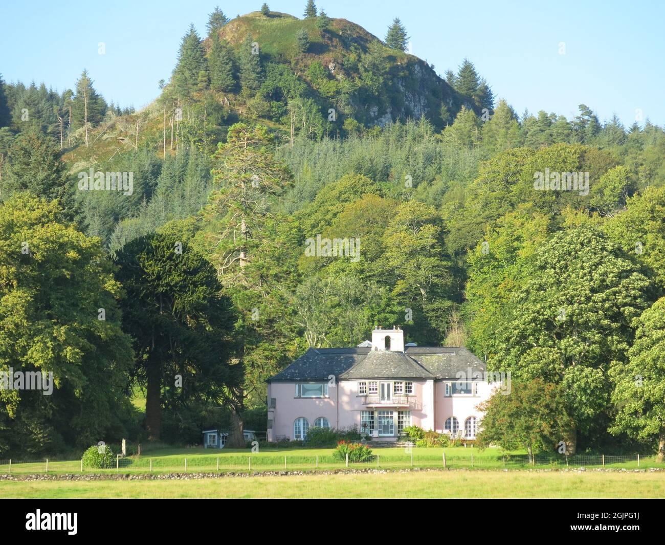 Soft pink render on the walls of this Scottish country house, bathed in early evening sunlight, in the romantic setting of Loch Melfort countryside. Stock Photo