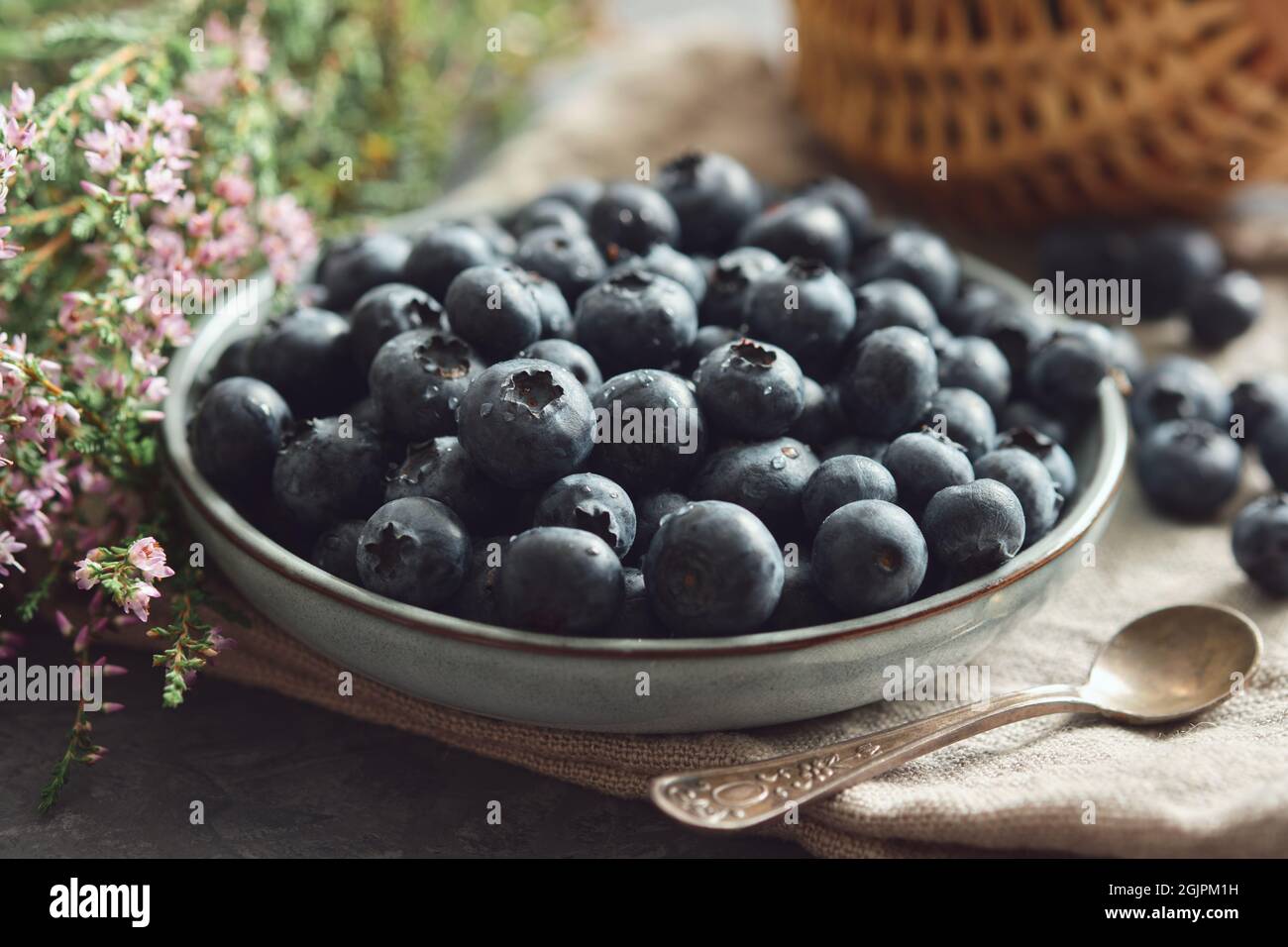 Blue plate of fresh blueberries and heather flowers on kitchen table. Stock Photo