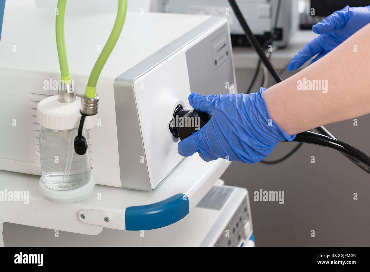 Preparation of equipment for the medical examination of video gastroscopy. The doctors hands in blue gloves connect the endoscope and other equipment Stock Photo