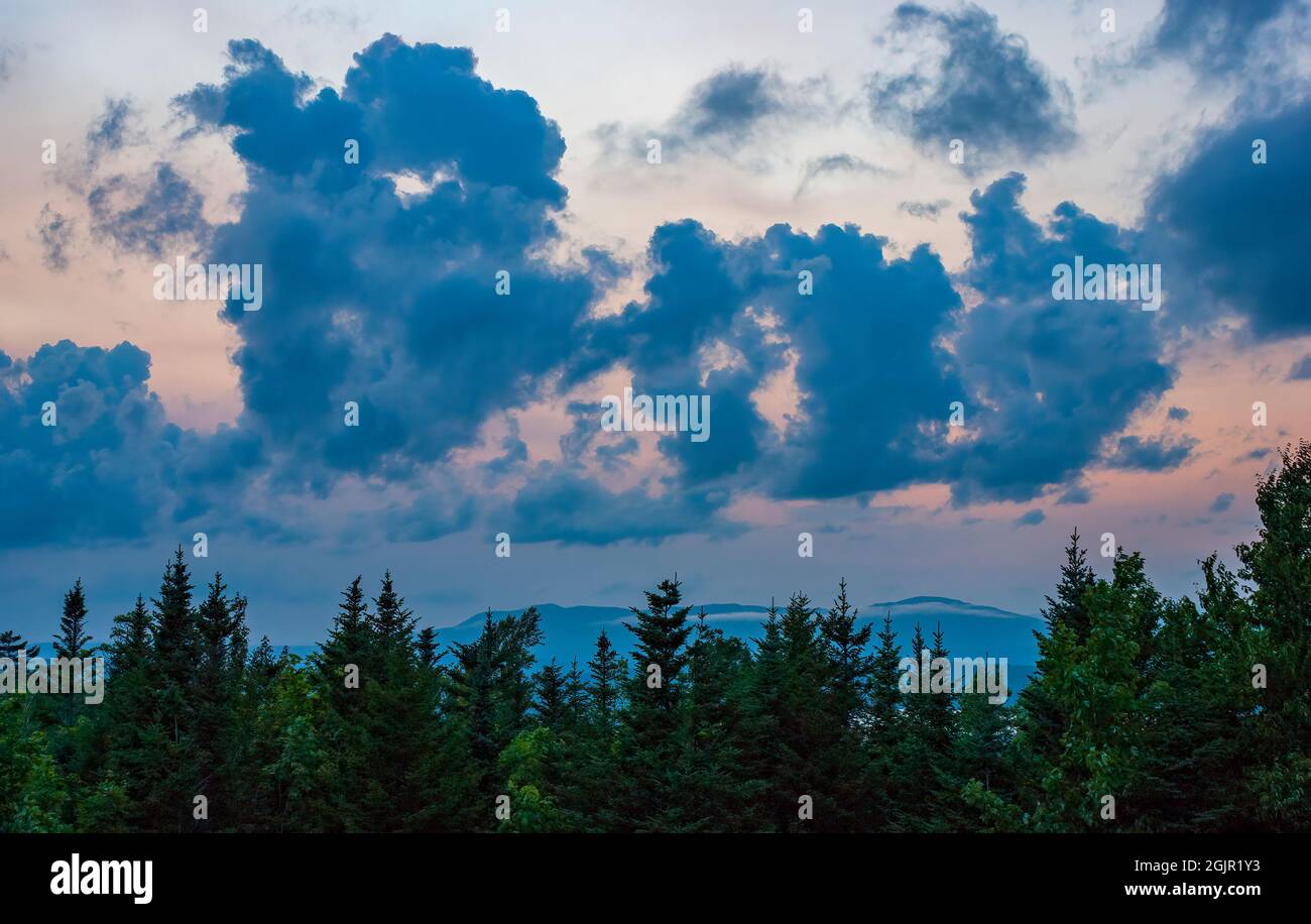 Sunset cloudscape over Rangeley Lake, ME, US. Stratocumulus castellanus clouds above a black spruce-balsam fir forest. Mountain ridges on the horizon. Stock Photo