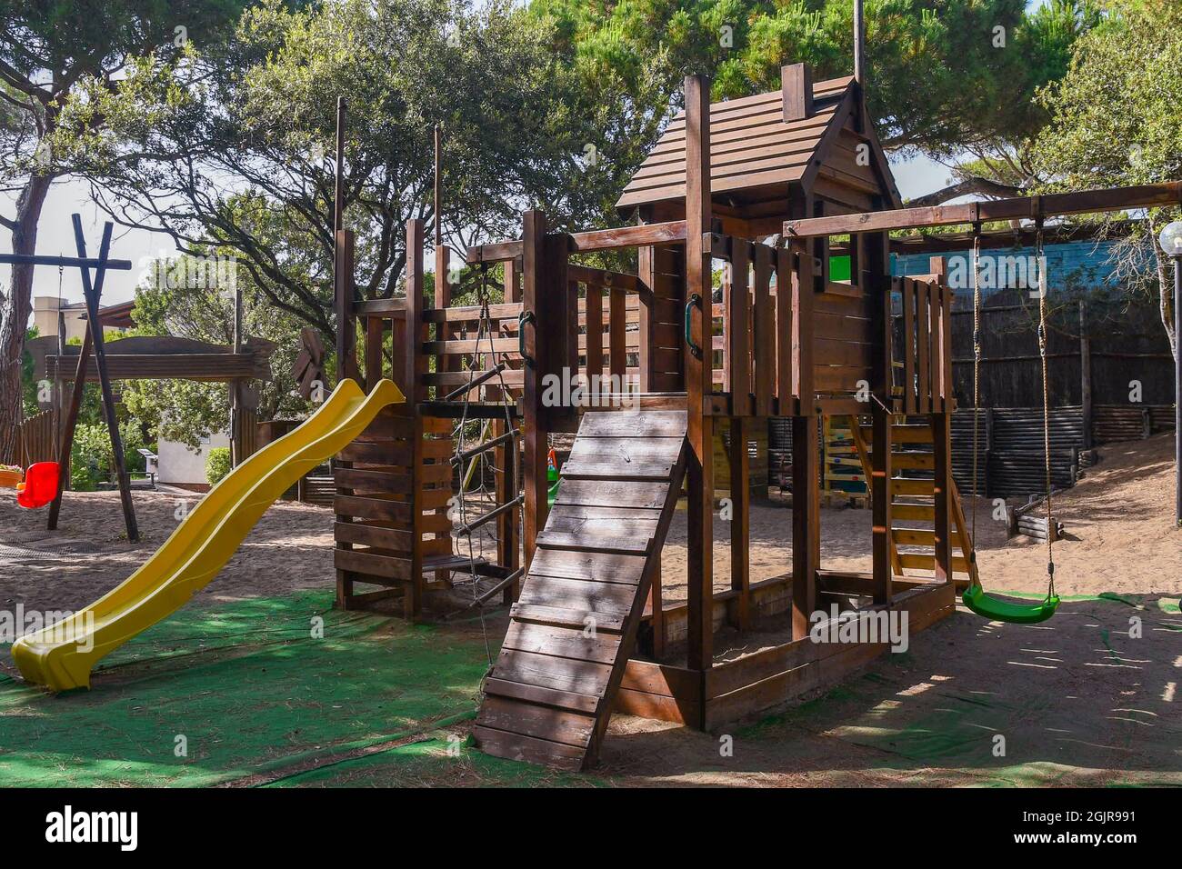 An empty children playground with slides, swings and various trails in a pine forest on the Tuscan coast, Castagneto Carducci, Livorno, Italy Stock Photo