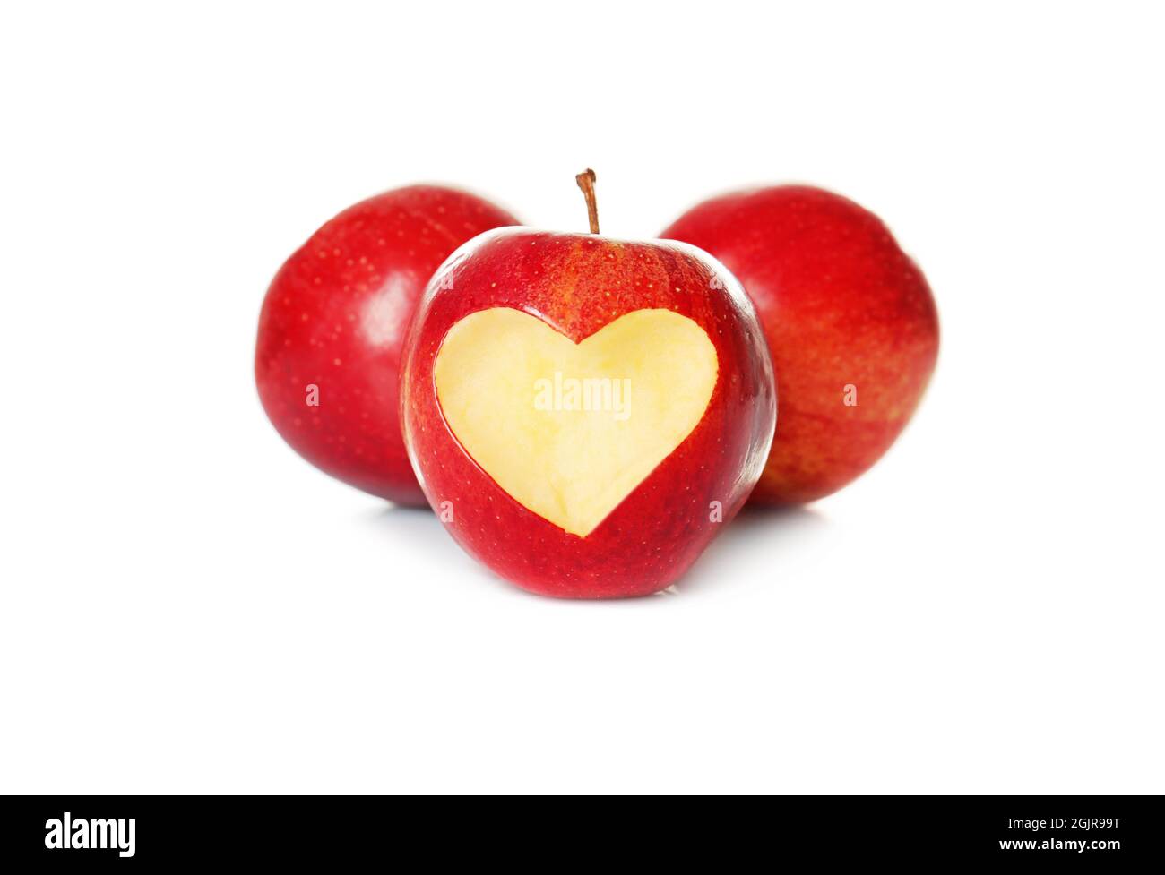 Fresh red apples and one with heartshaped cut out on white background